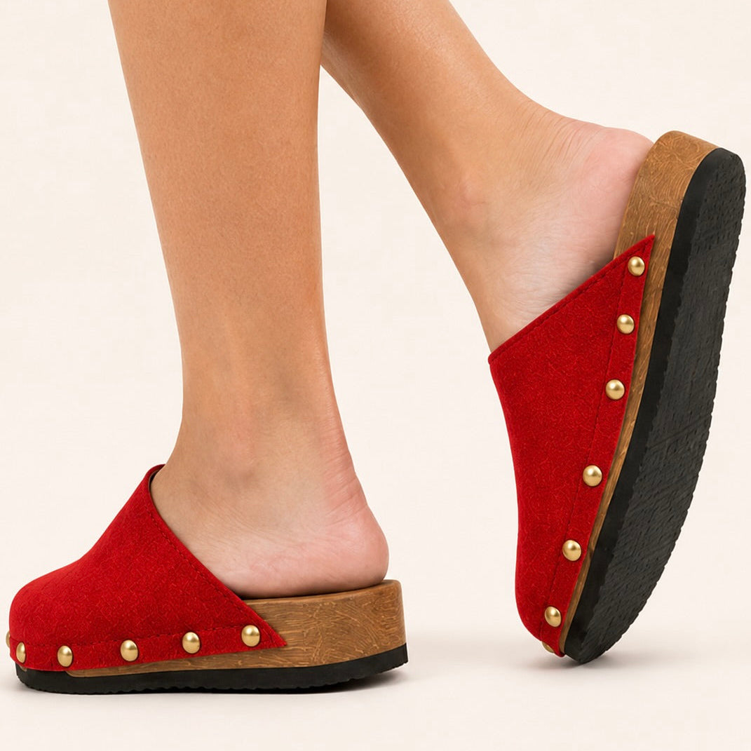 Pair of postkasse rød suede studs clogs on a white background