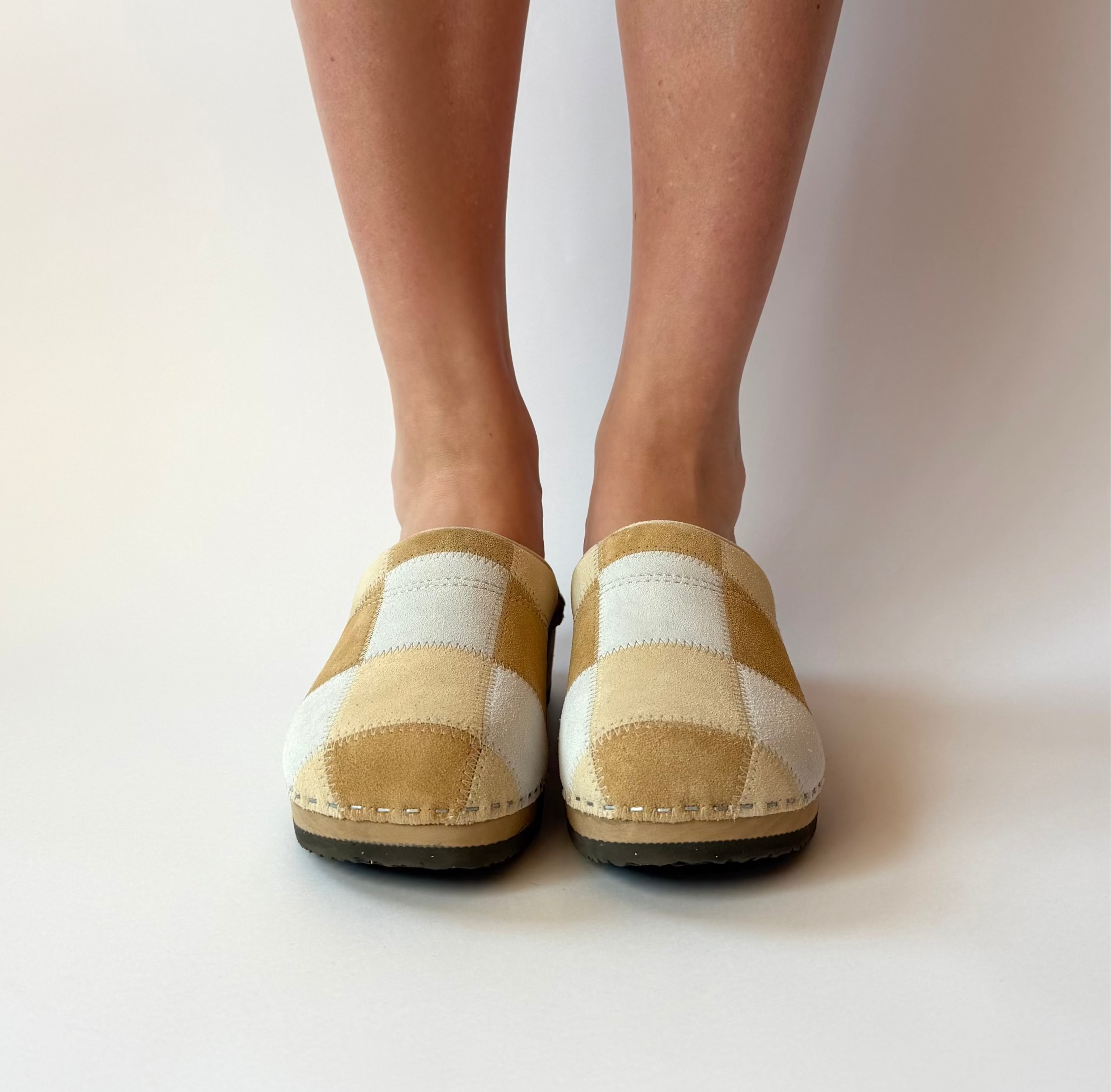 Checkered slip-on shoes worn by a person on a plain background