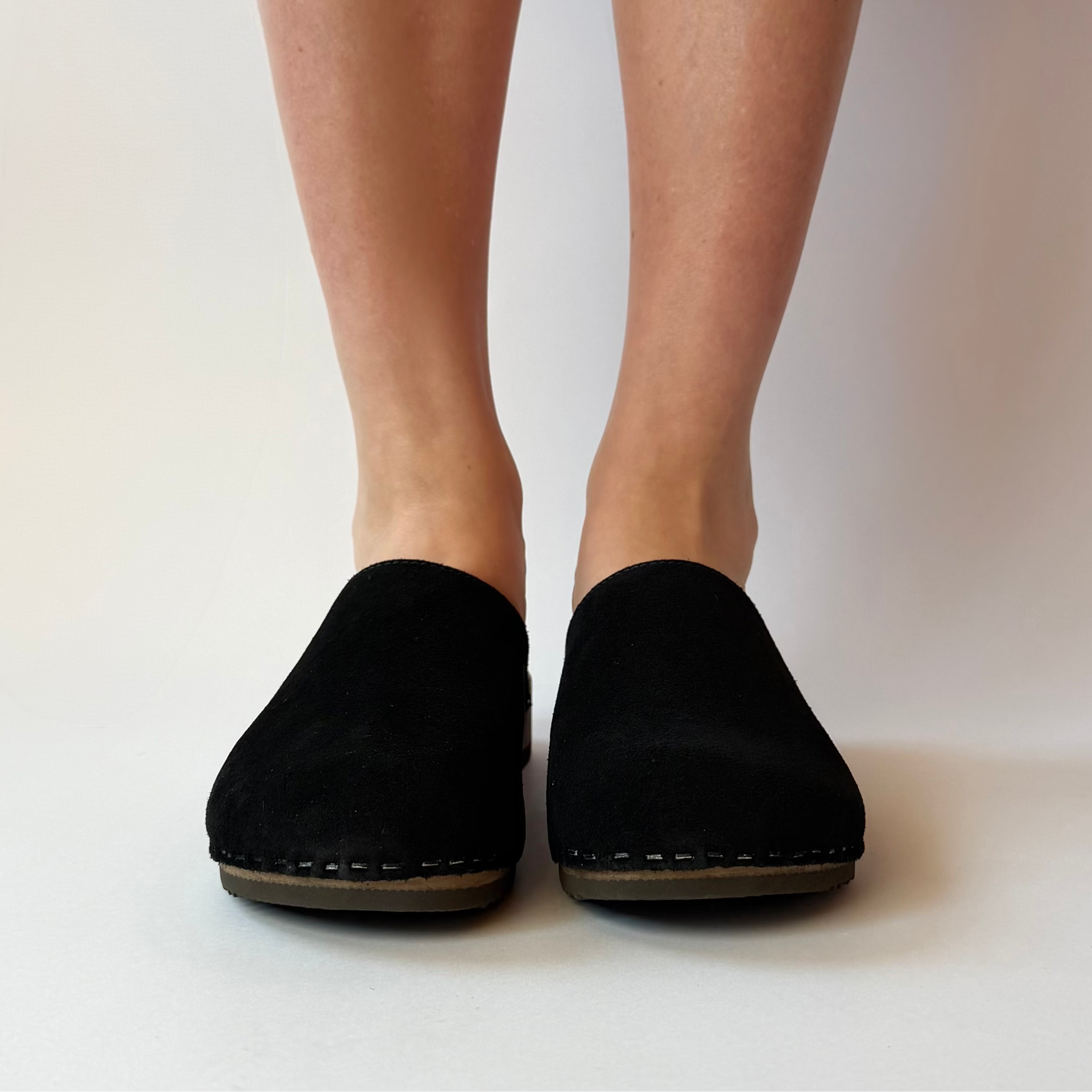 Black slippers worn by a person on a white background