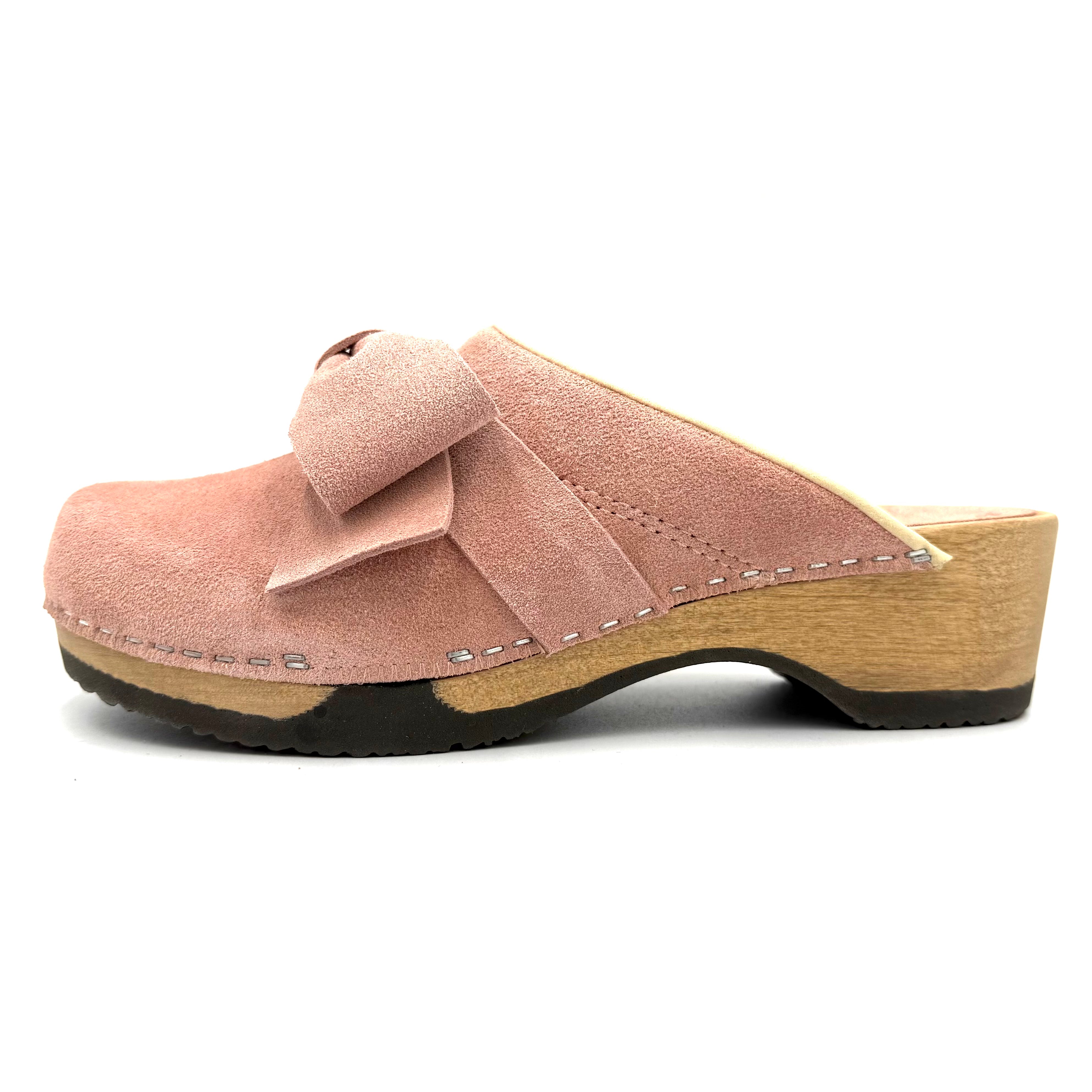 Pink suede clog shoe with a wooden sole on a white background