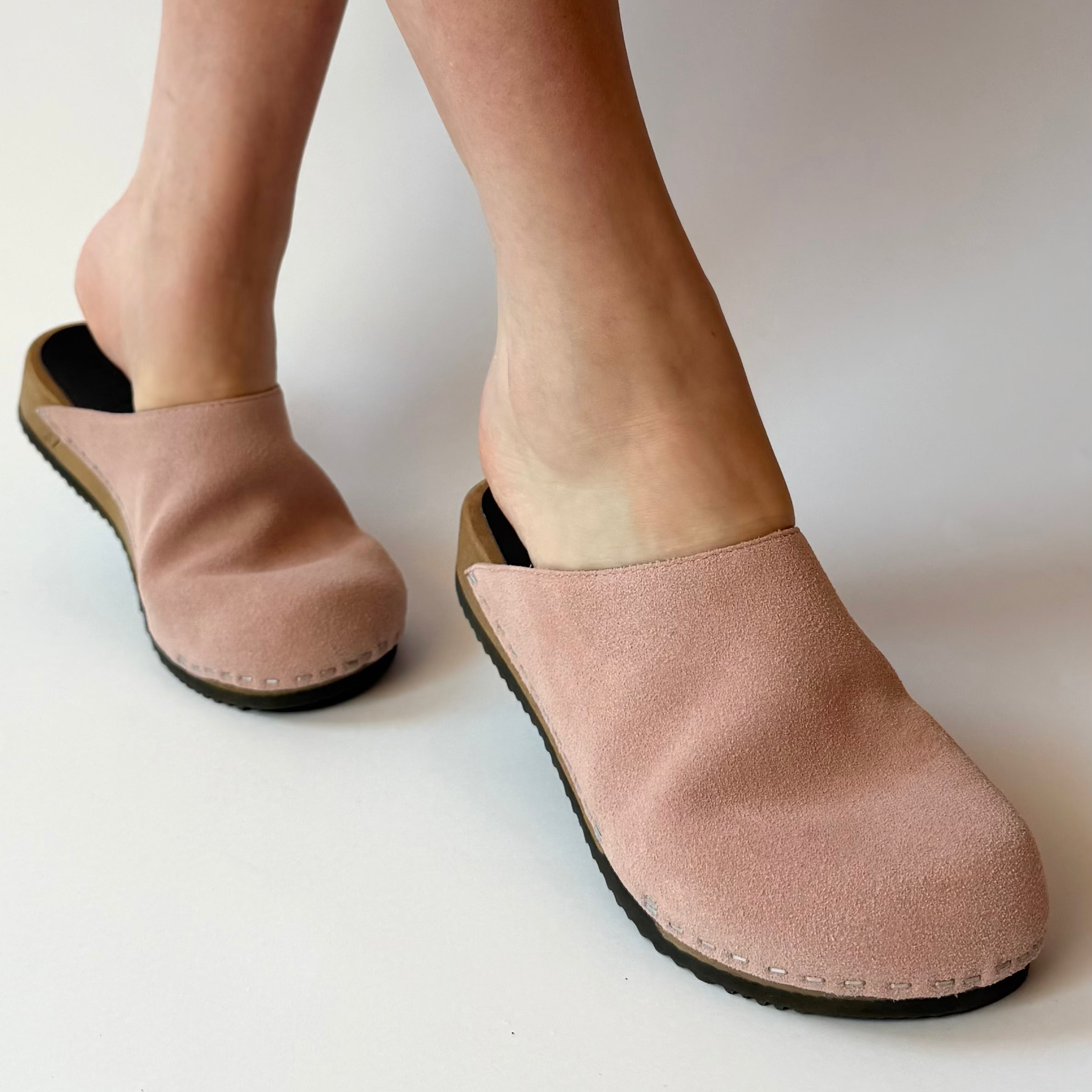 Pink slippers worn by a person on a white background