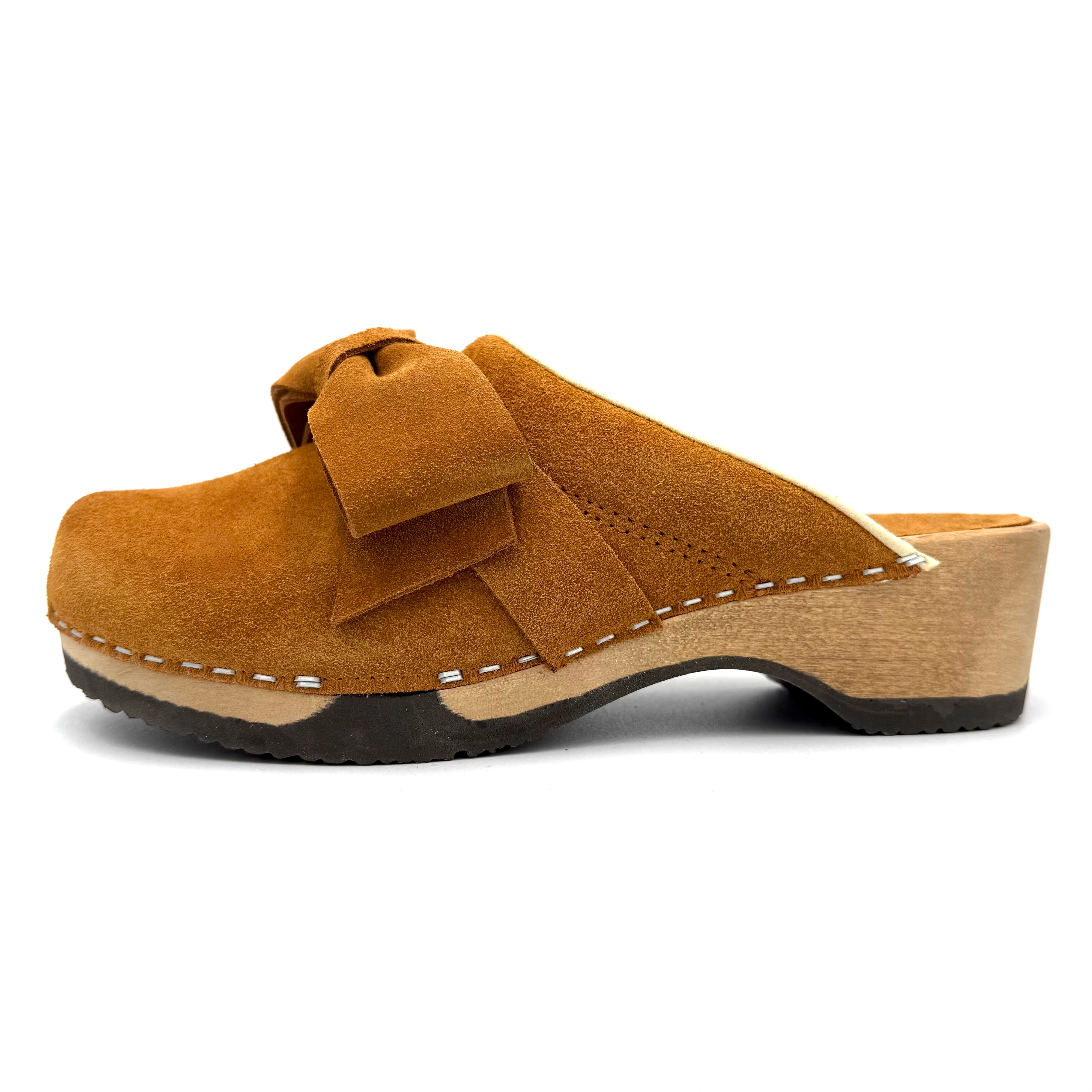 Brown suede clog shoe with a bow on a white background