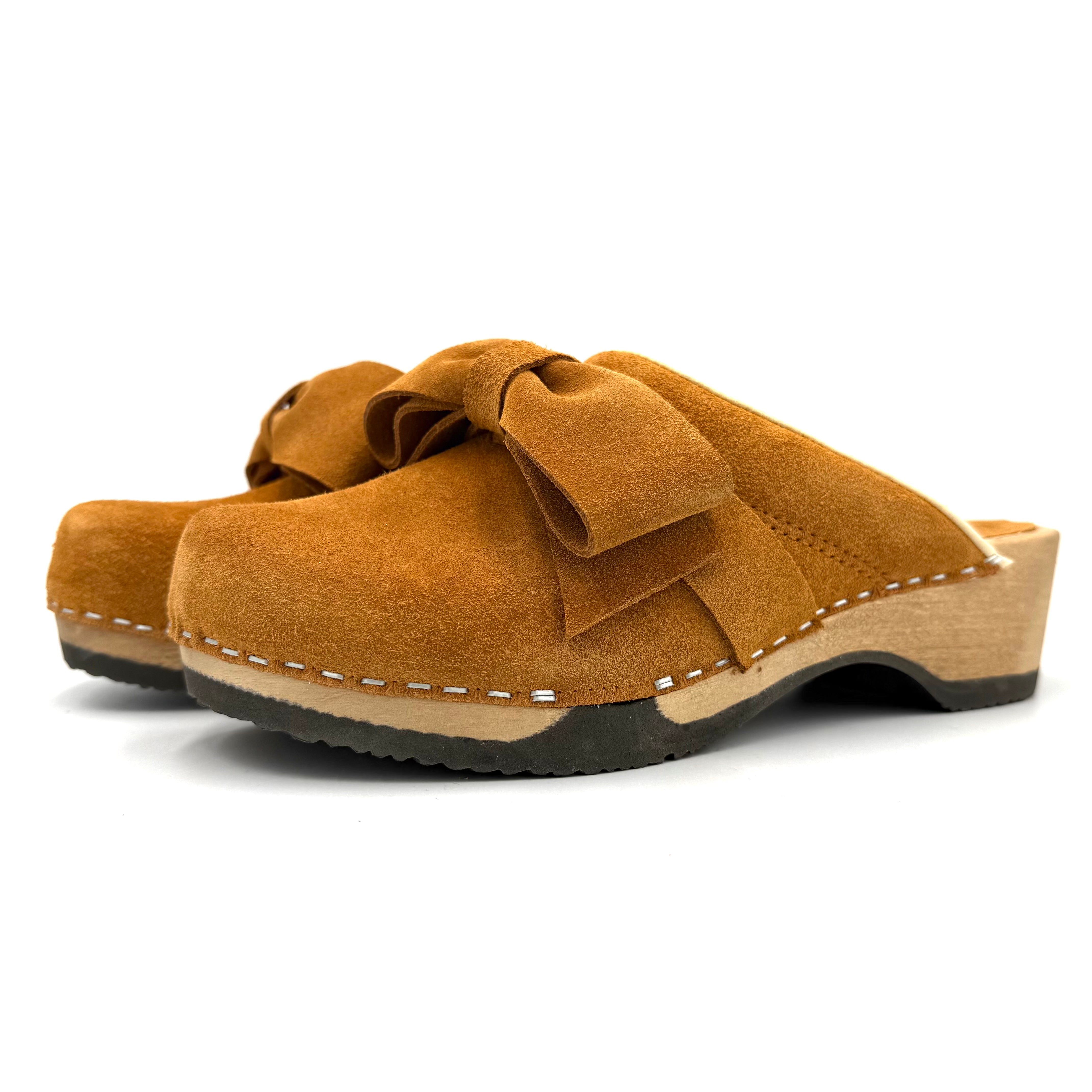Brown suede clog shoe with a bow on a white background