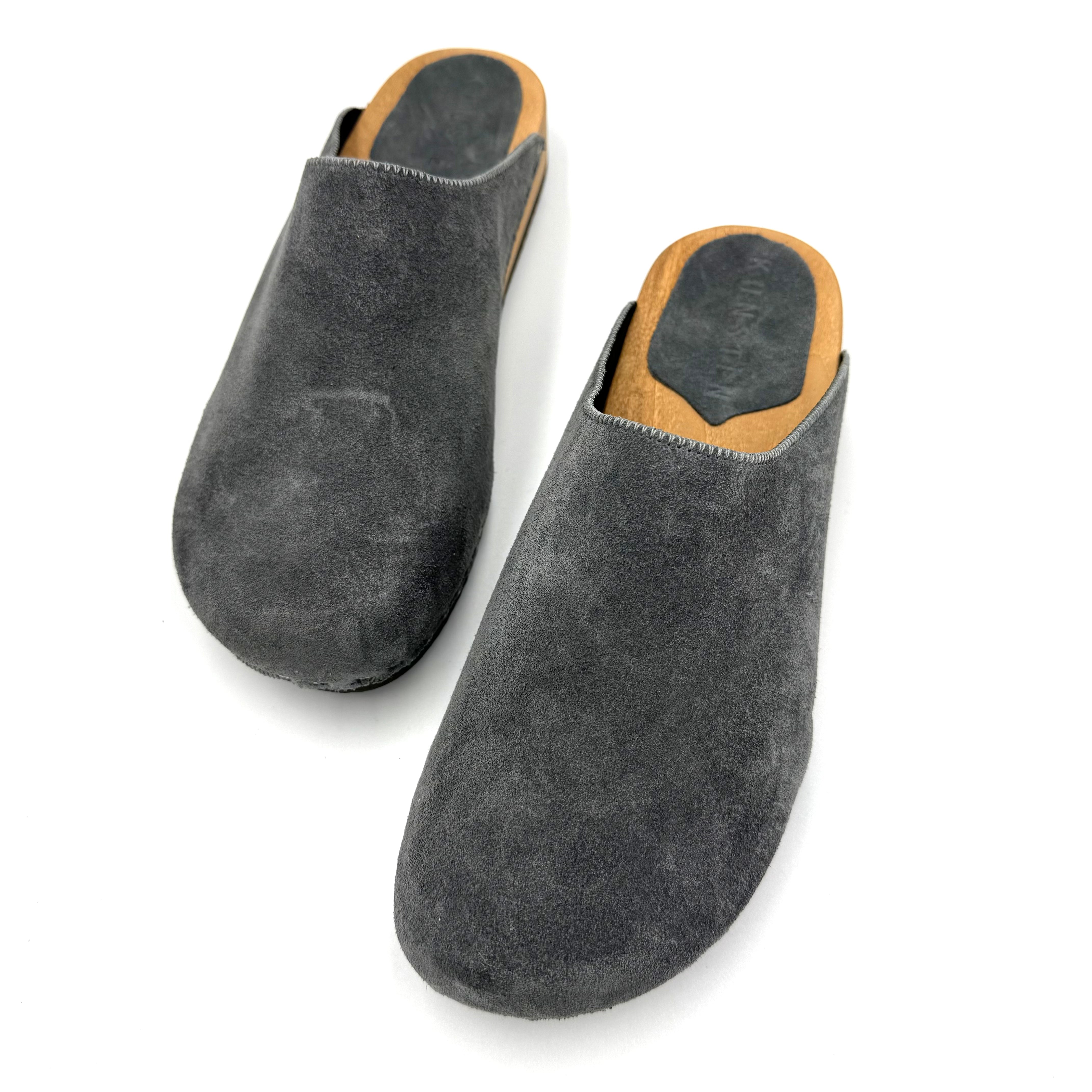 Pair of gray suede slippers with brown soles on a white background