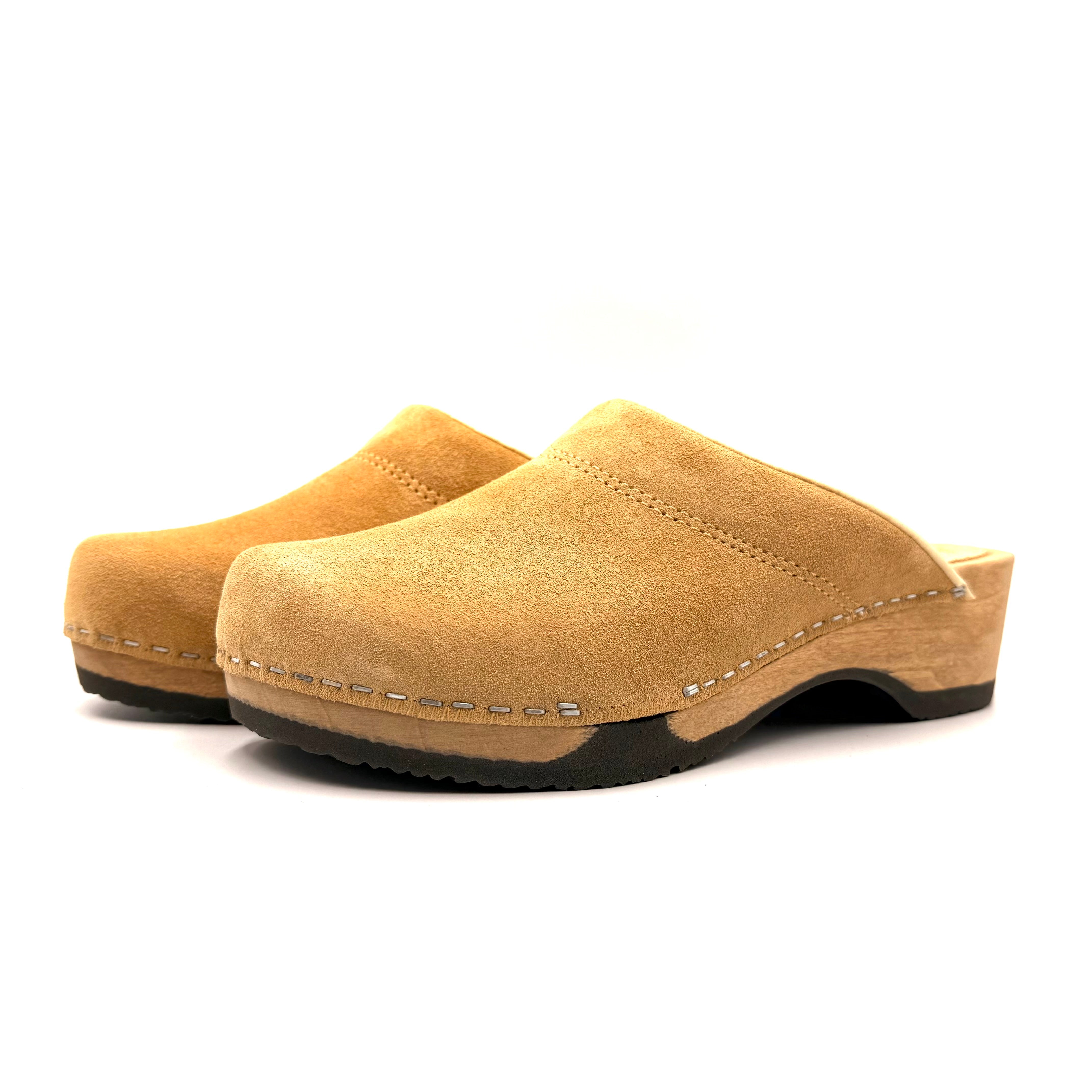Pair of tan suede clogs on a white background