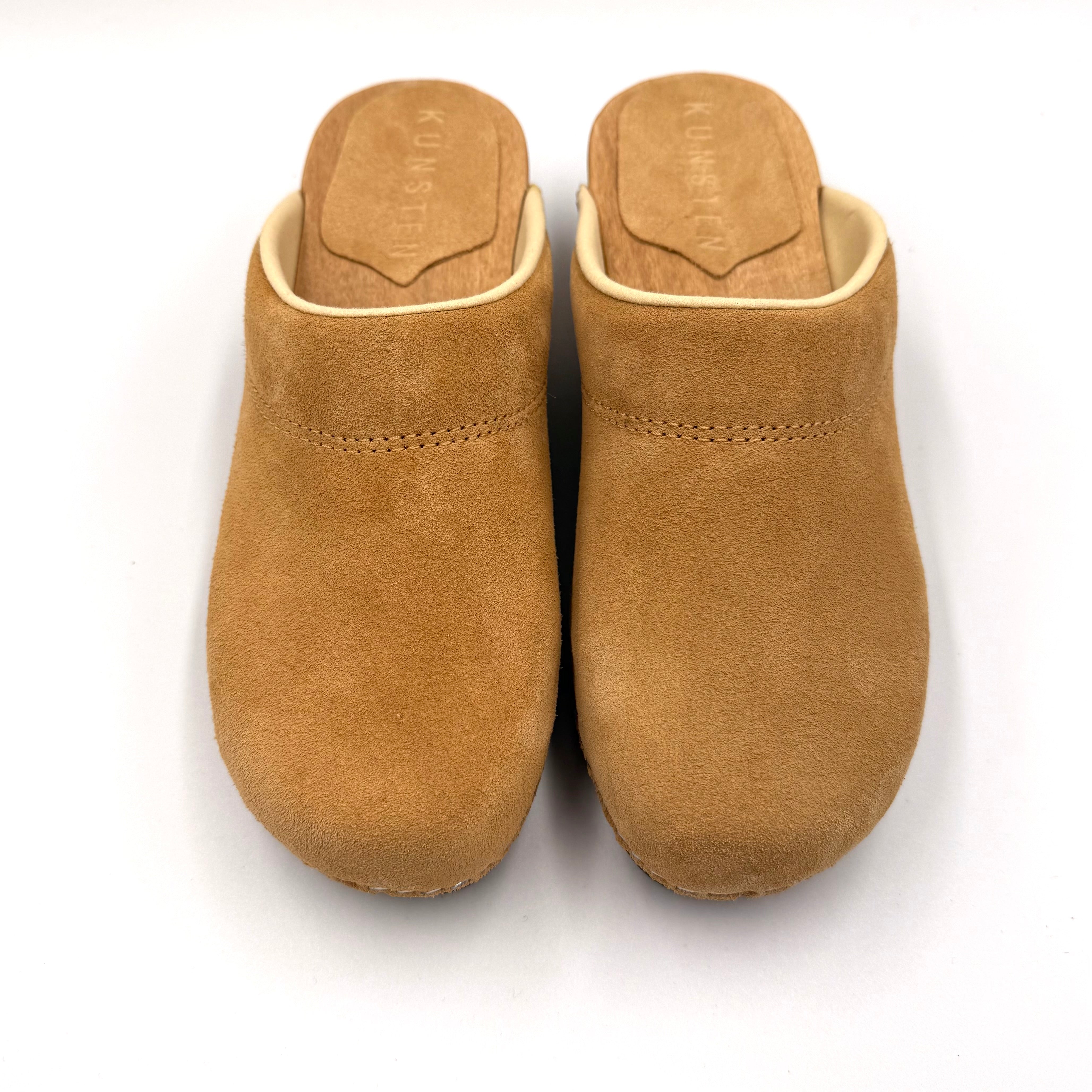 Pair of tan clogs on a white background