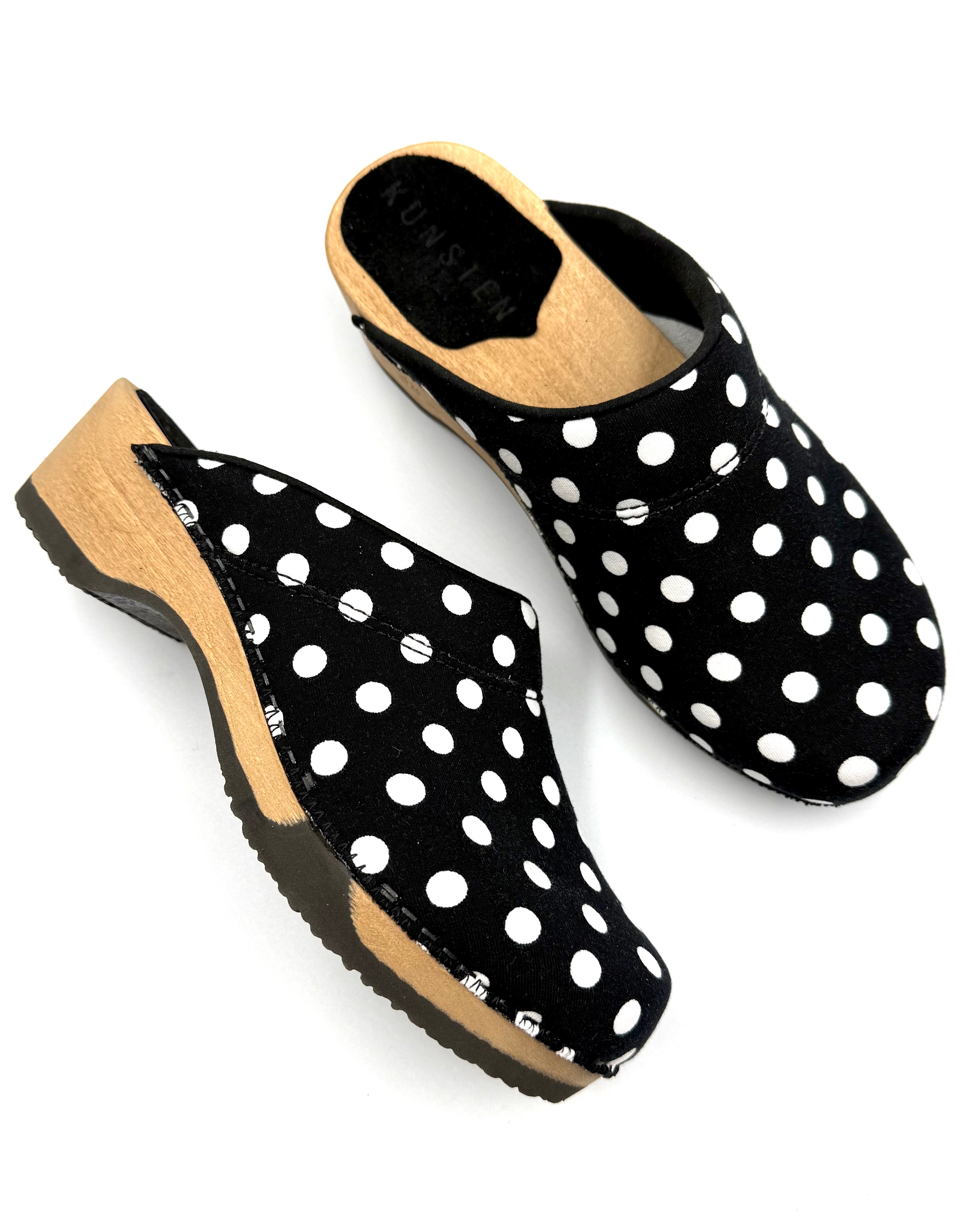Black clogs with white polka dots on a white background