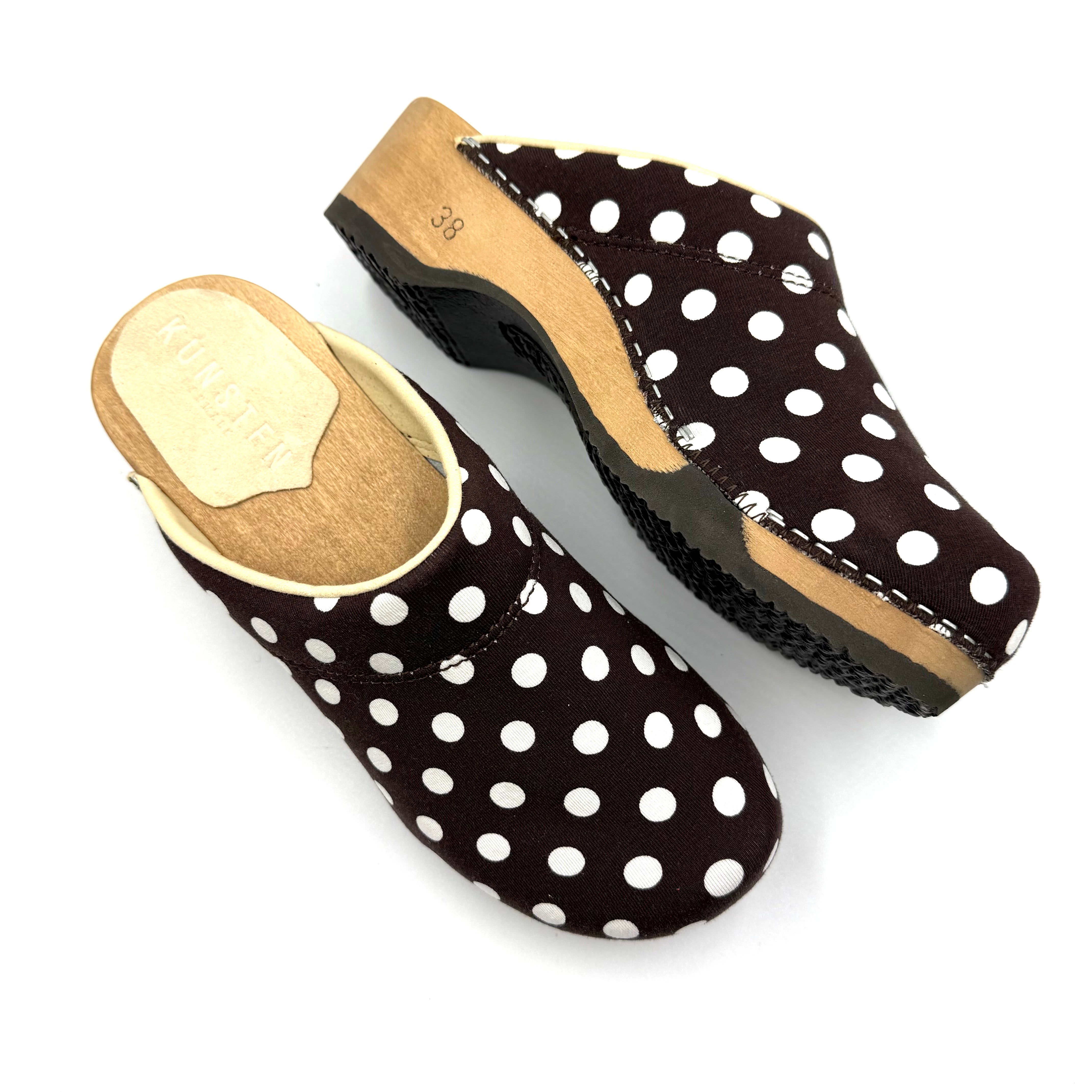 Pair of black clogs with white polka dots on a white background