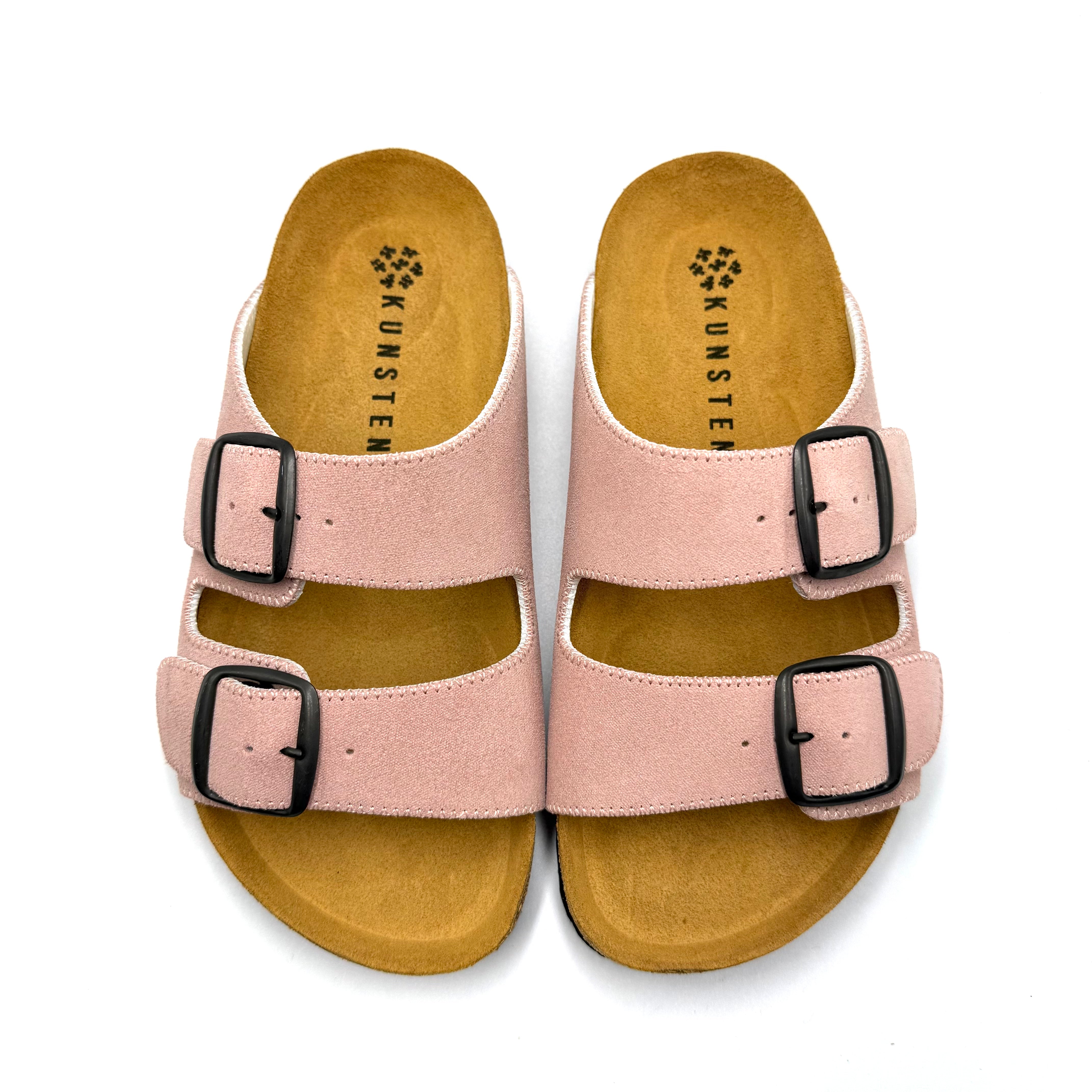 Pair of pink sandals with black buckles on a white background