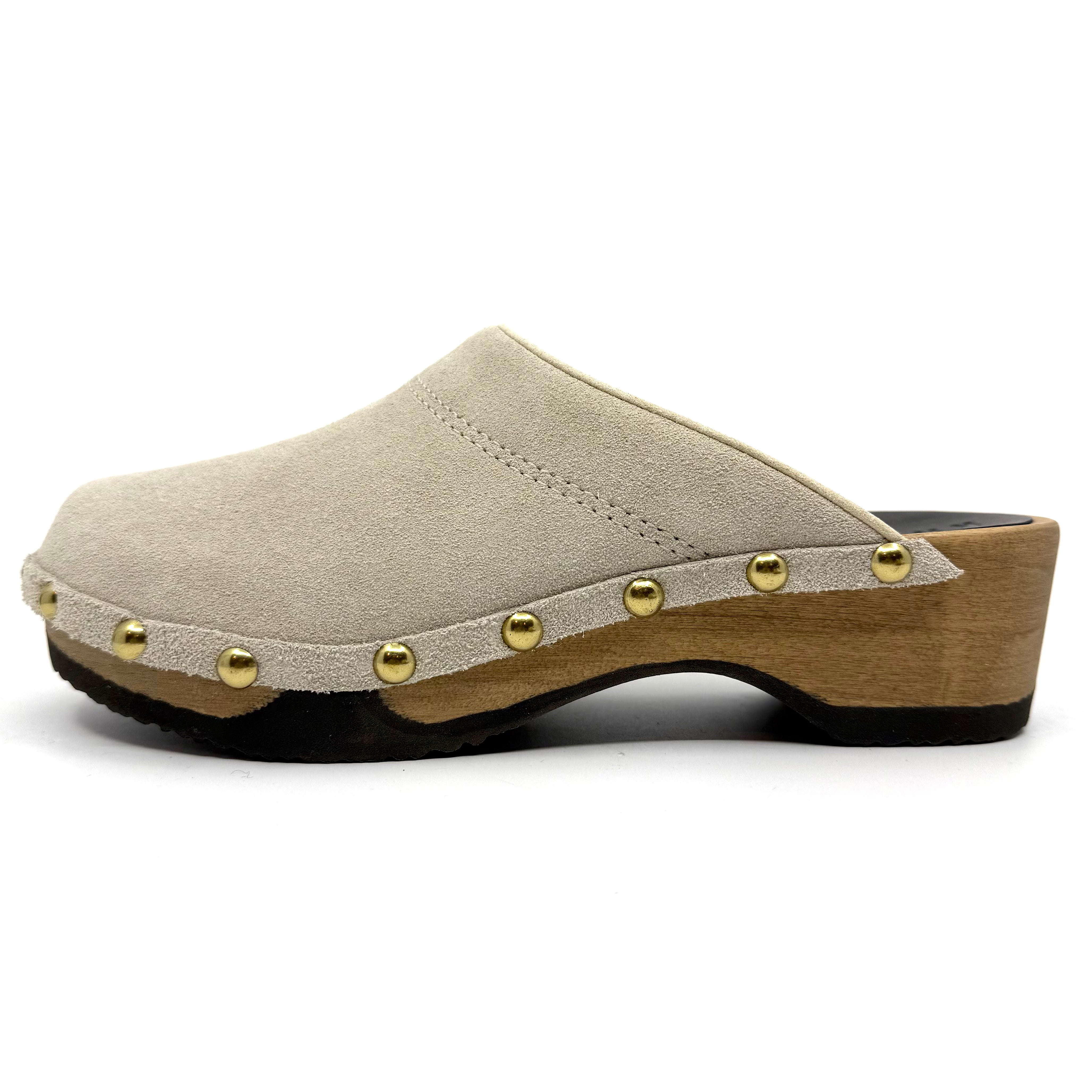 Beige clog shoe with wooden sole and gold studs on a white background