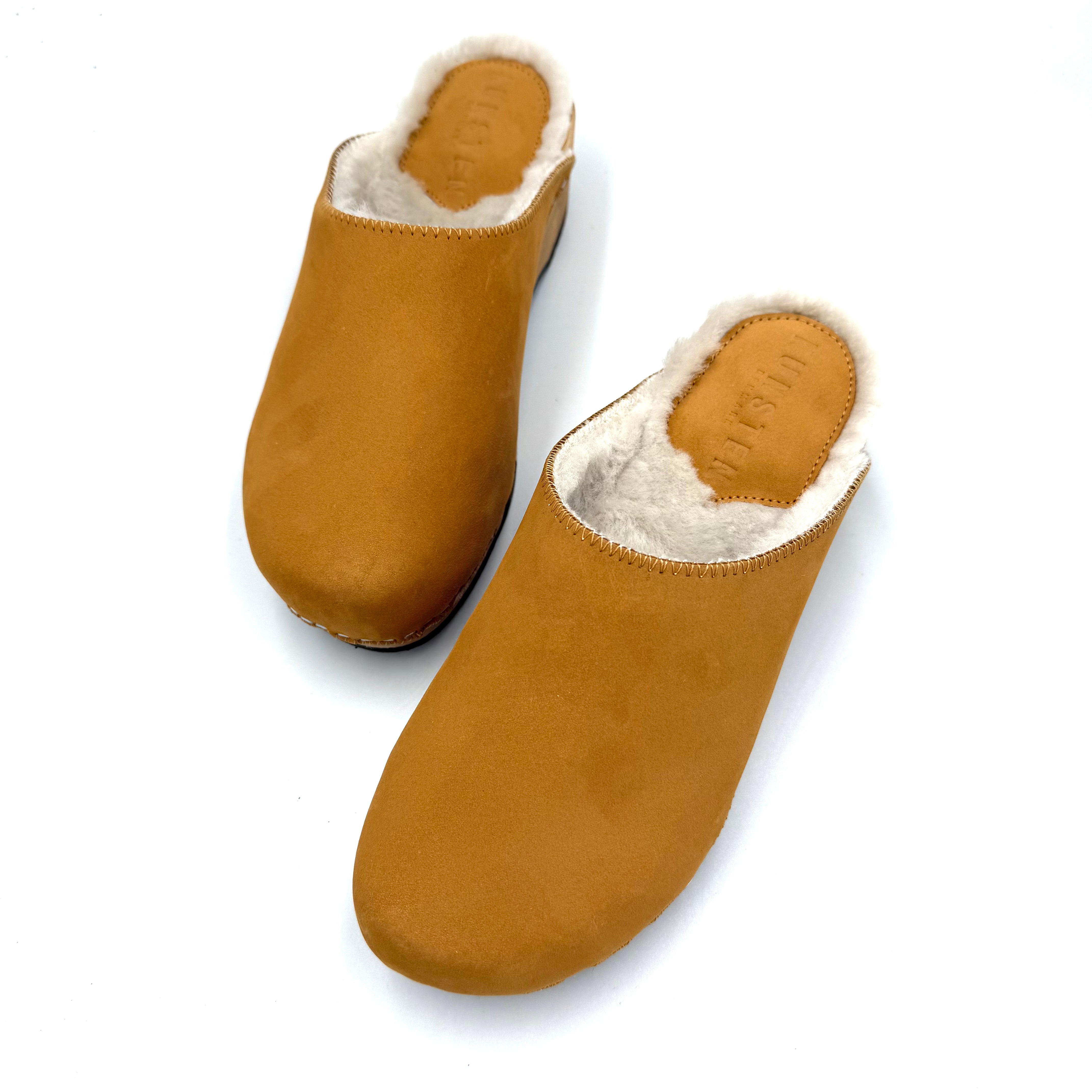 Pair of brown slippers with white fur lining on a white background