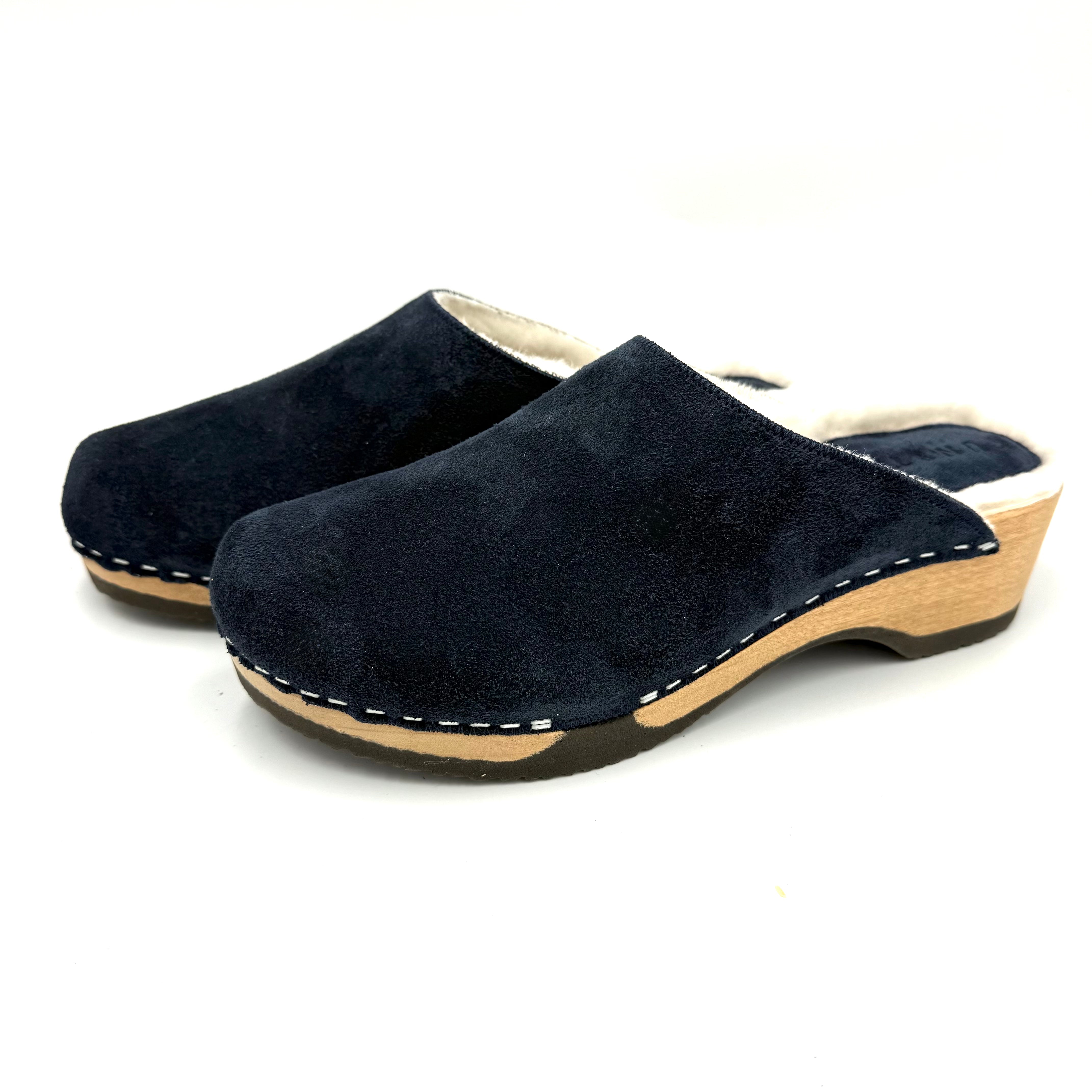 Pair of navy blue suede clogs with wooden soles on a white background