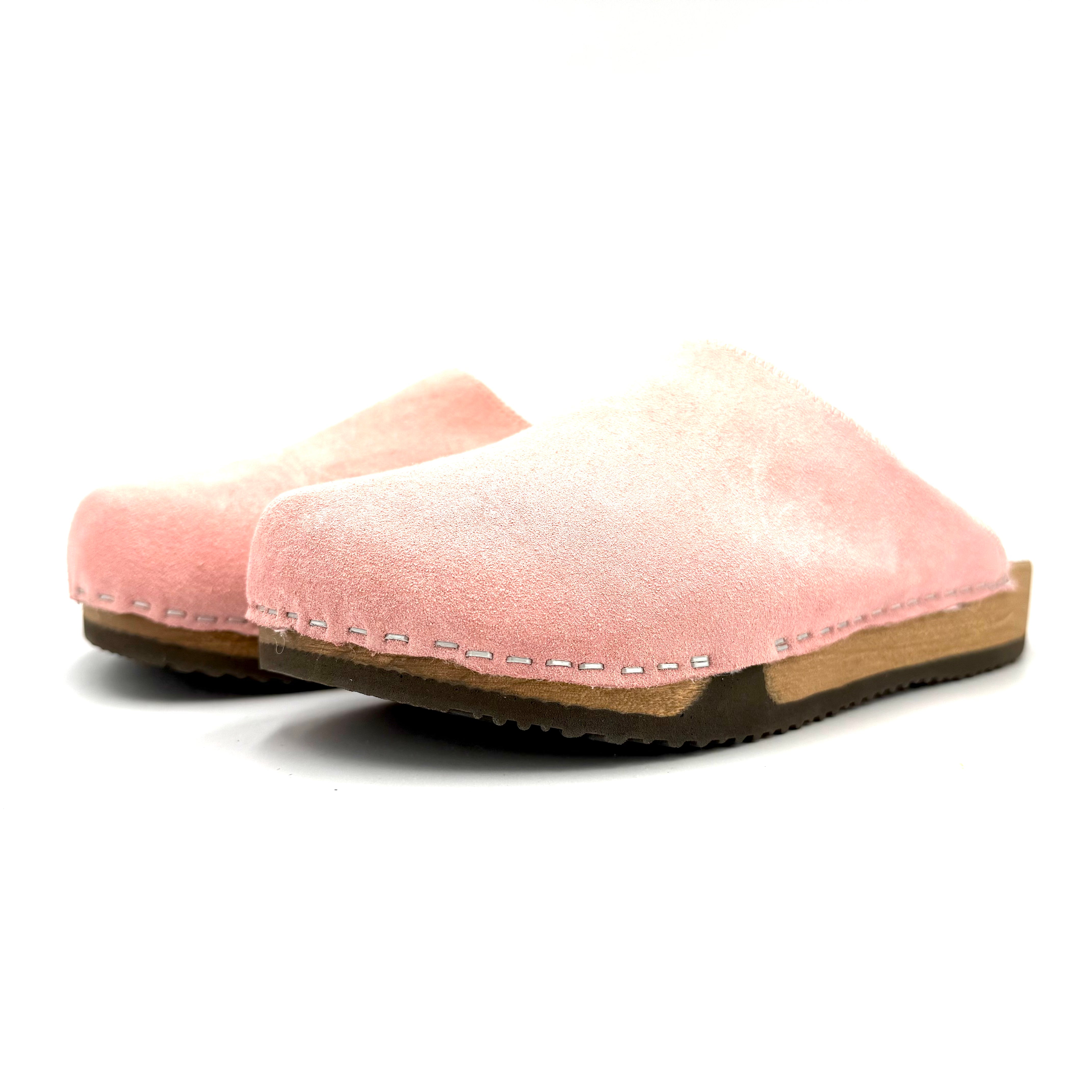 Pair of pink slippers with a wooden sole on a white background