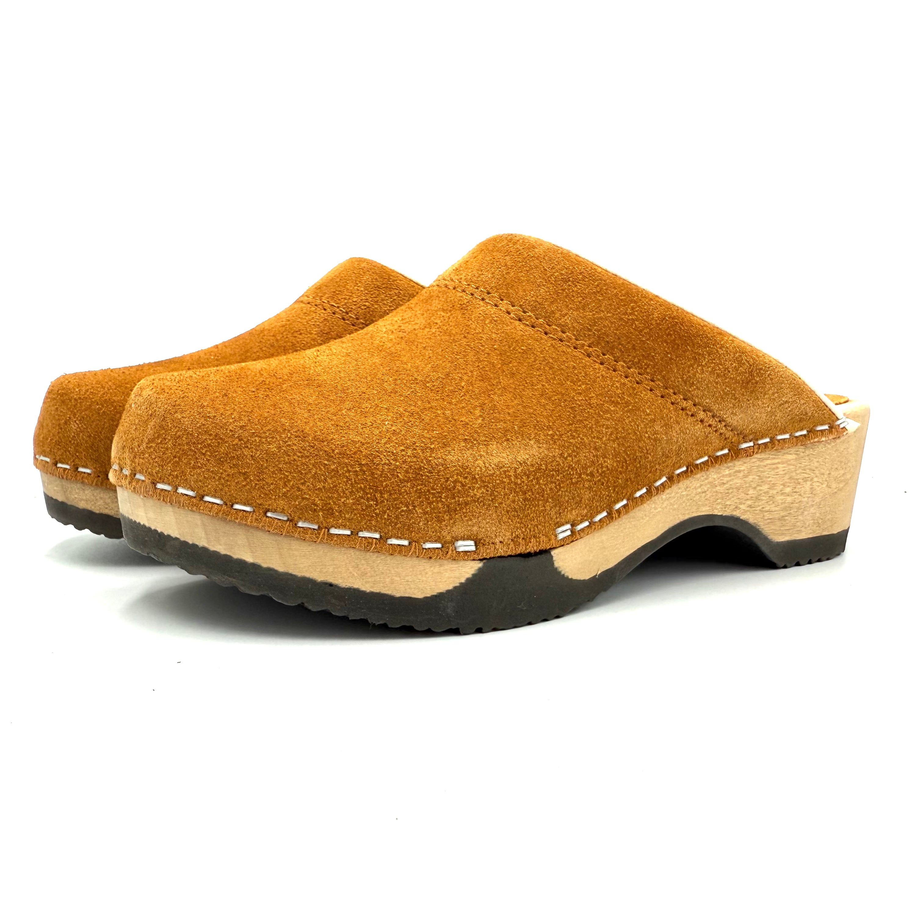 Pair of brown suede clogs on a white background