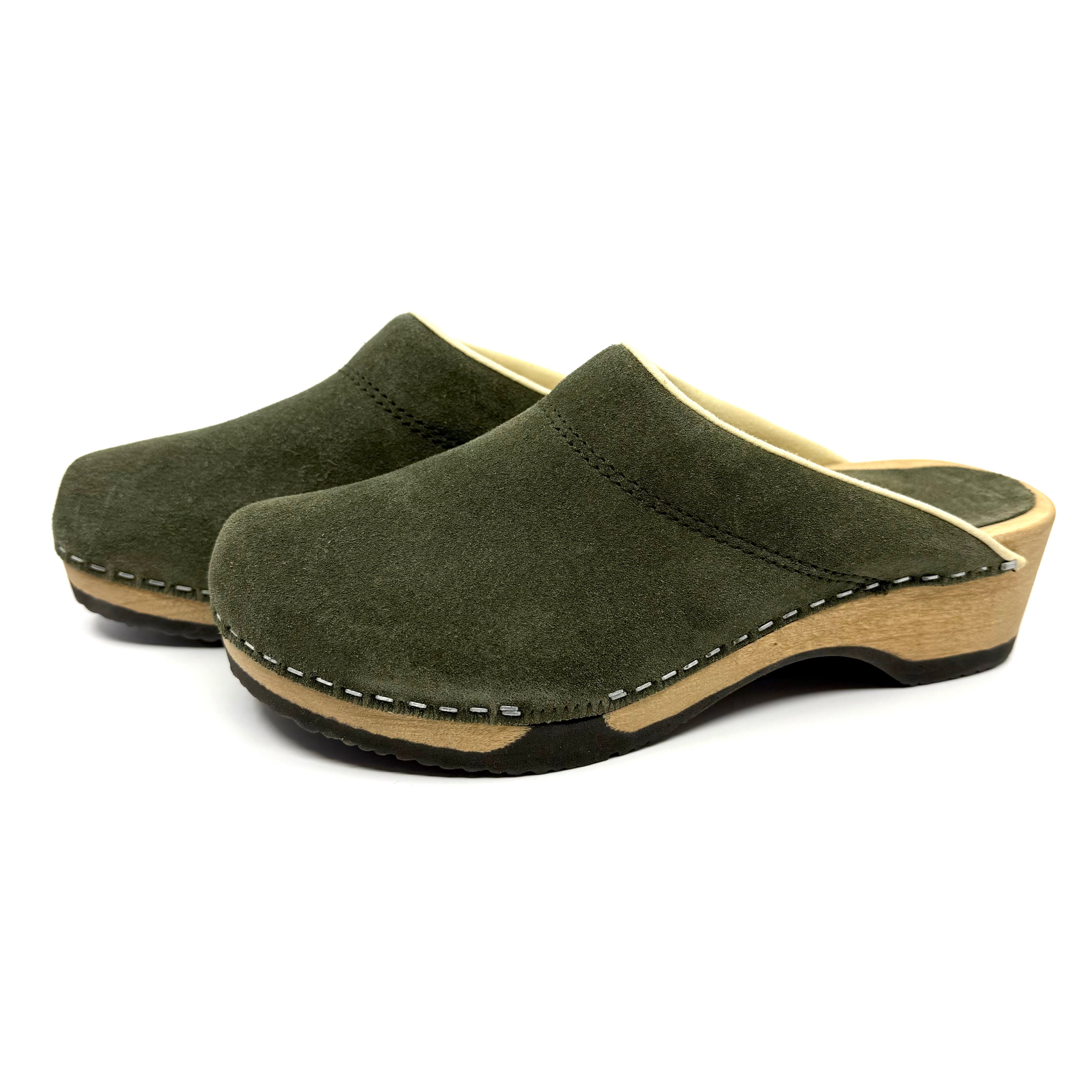 Pair of green suede clogs with wooden sole on a white background