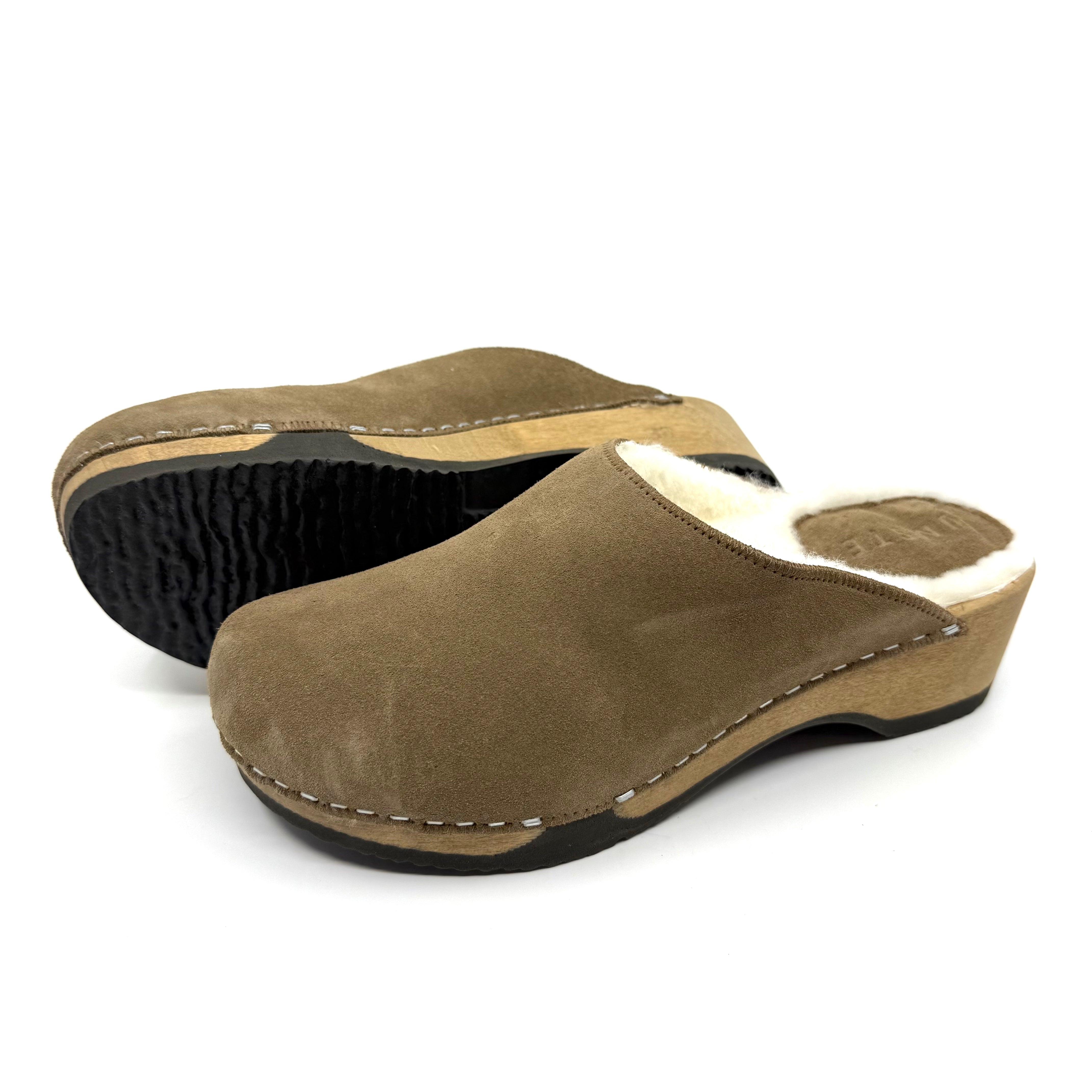 Pair of brown suede clogs on a white background
