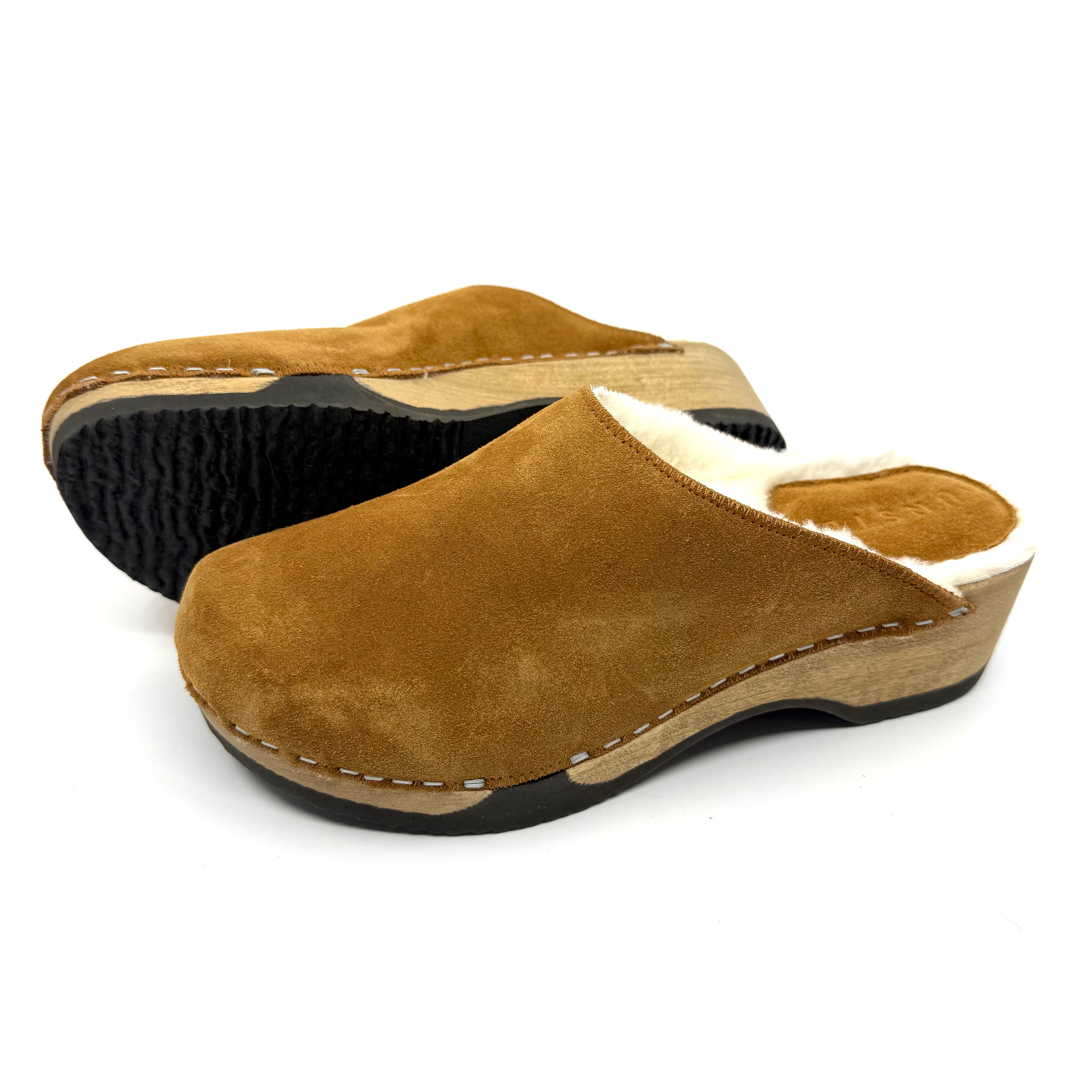Pair of brown suede clogs on a white background
