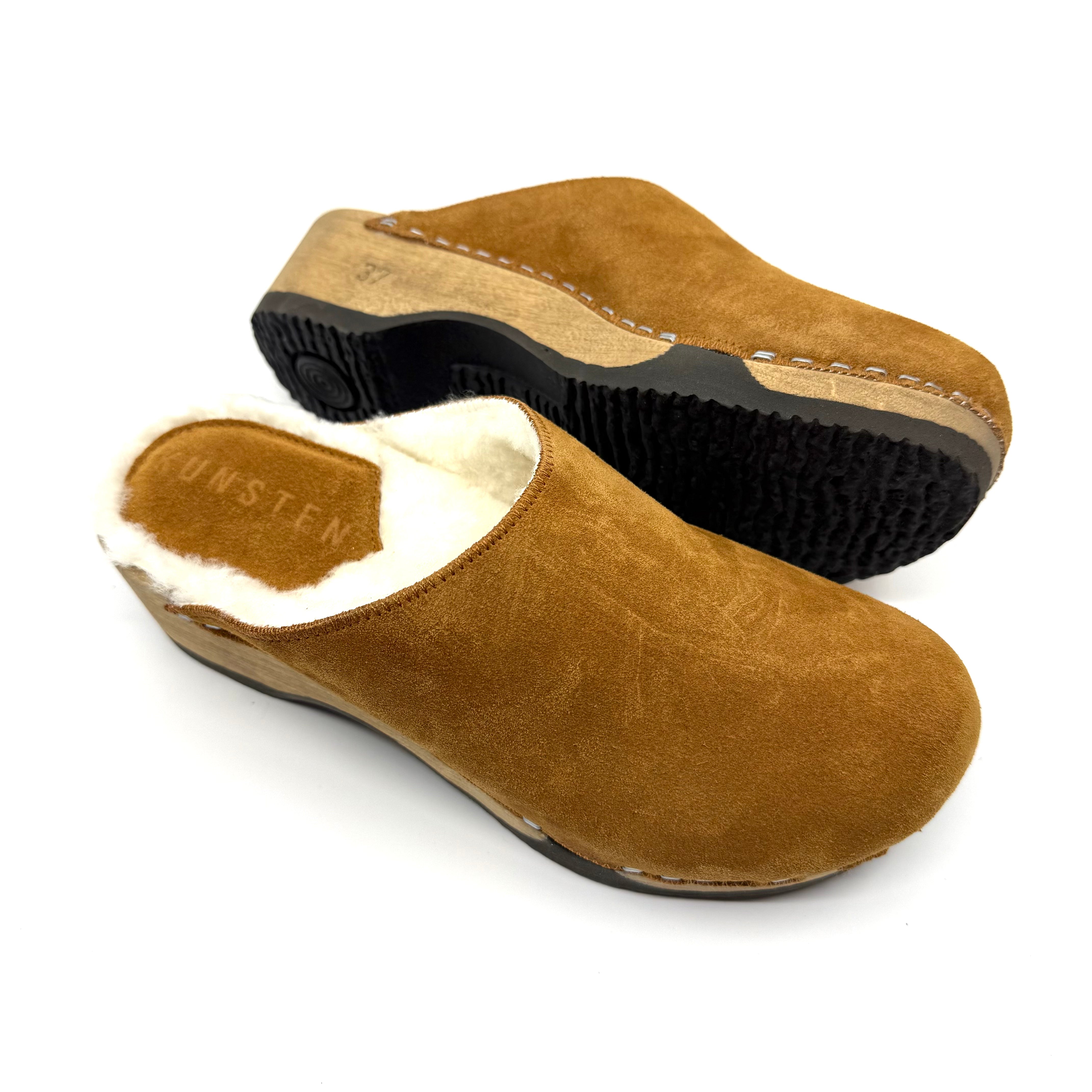 Pair of brown suede clogs with white fur lining on a white background