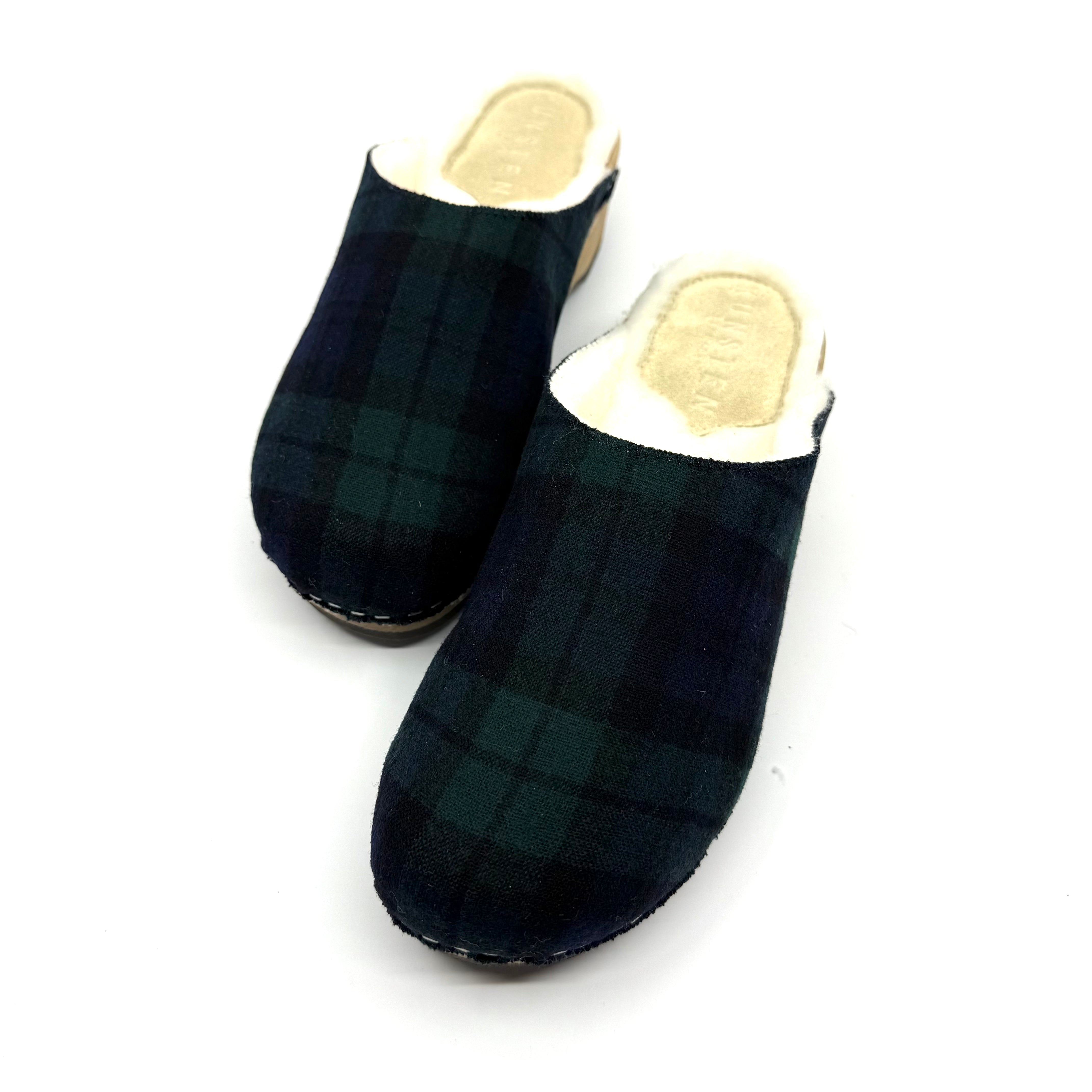 Pair of black and green plaid clogs on a white background