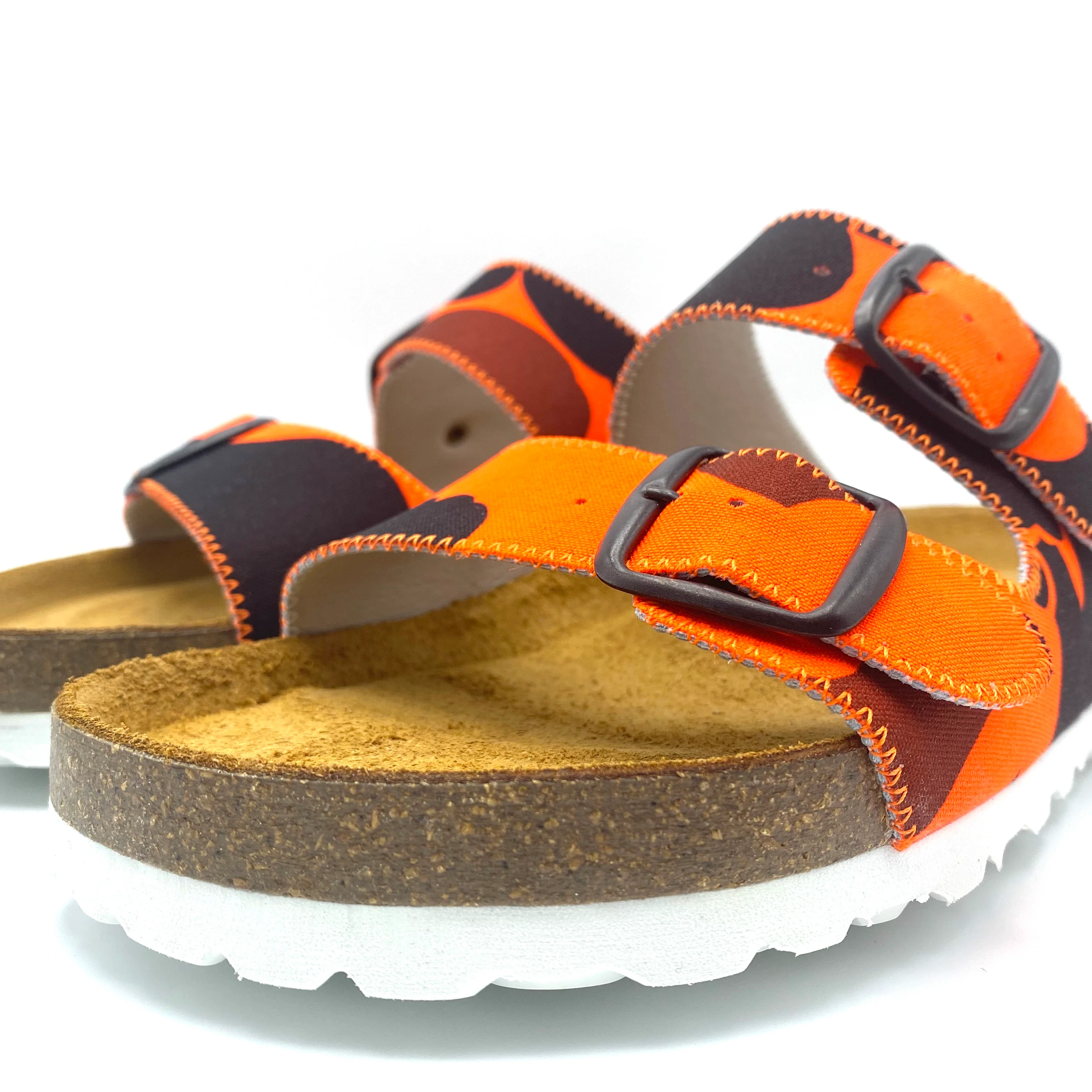 Orange and black sandals with cork sole on a white background