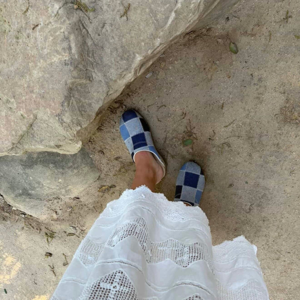 Close-up of a foot wearing a navy KUNSTEN clog on rocks
