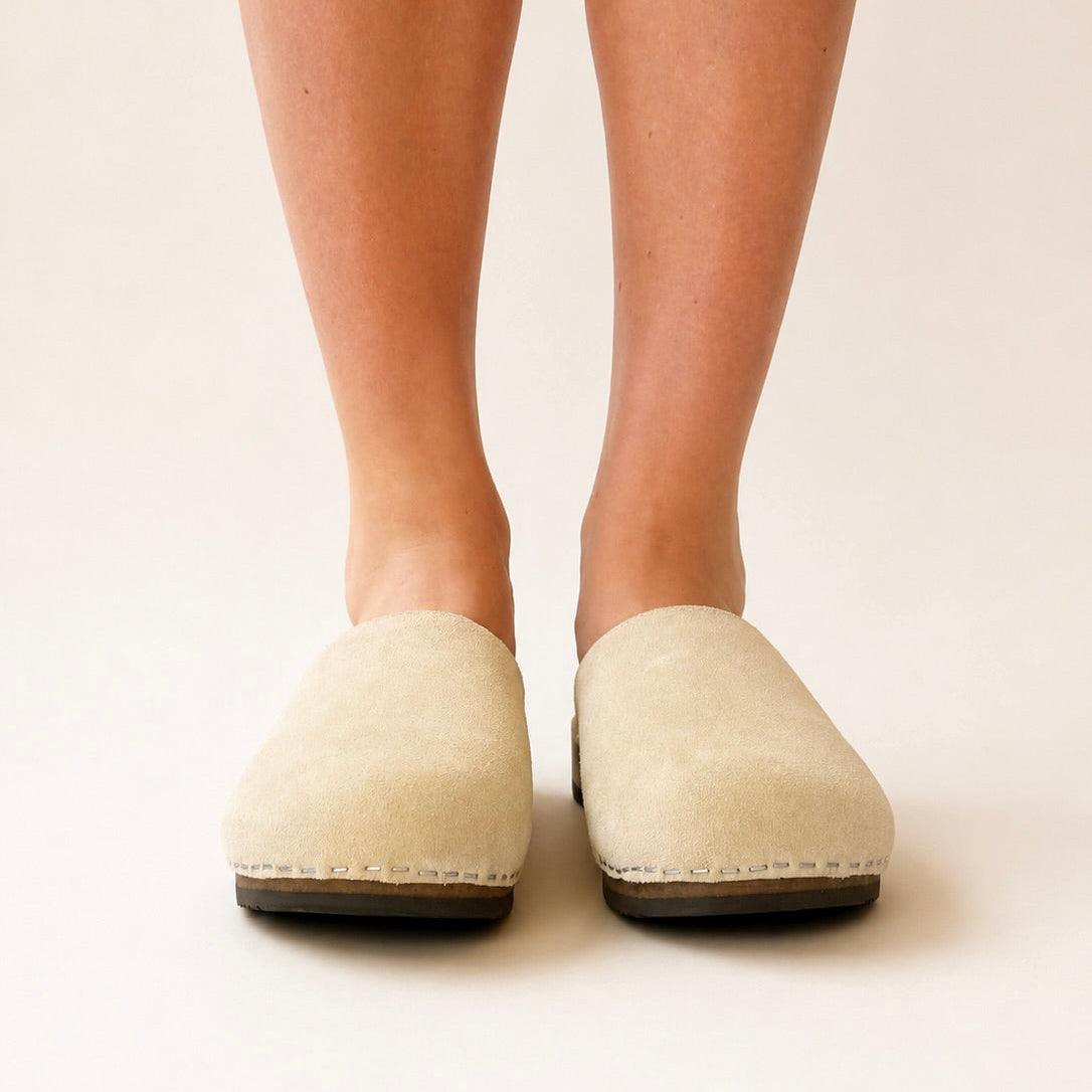 Pair of beige suede x pure lambswool clogs on a white background