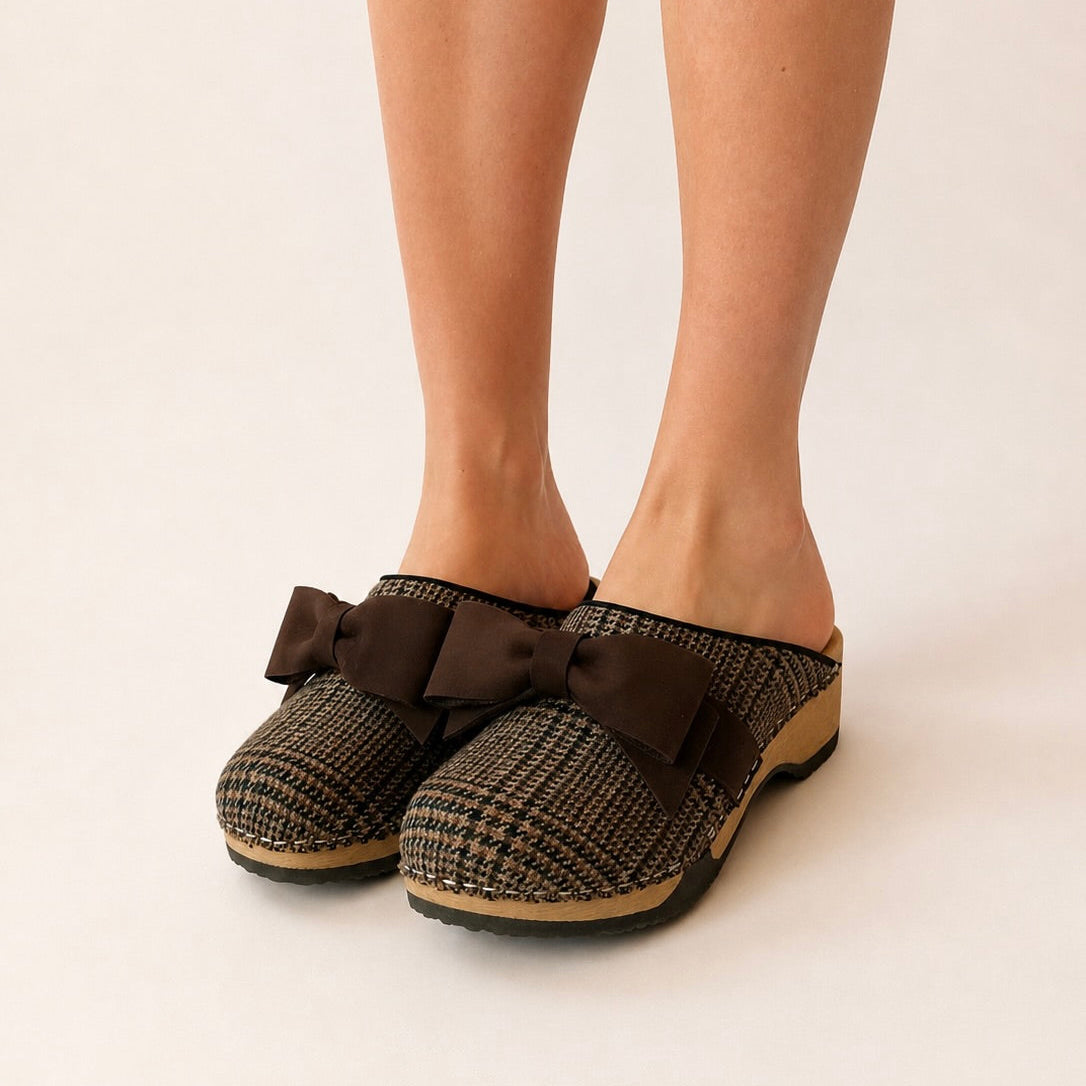 Pair of brown houndstooth slippers with large bows on a white background
