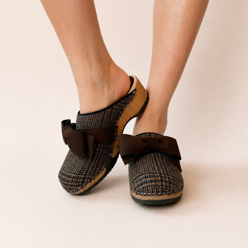 Pair of brown houndstooth patterned slippers with bows on a white background