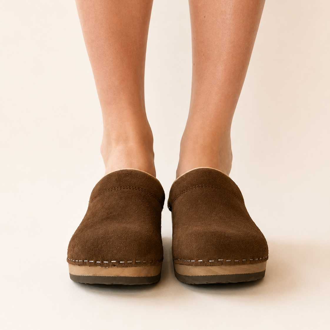 Pair of chocolate suede clogs on a white background