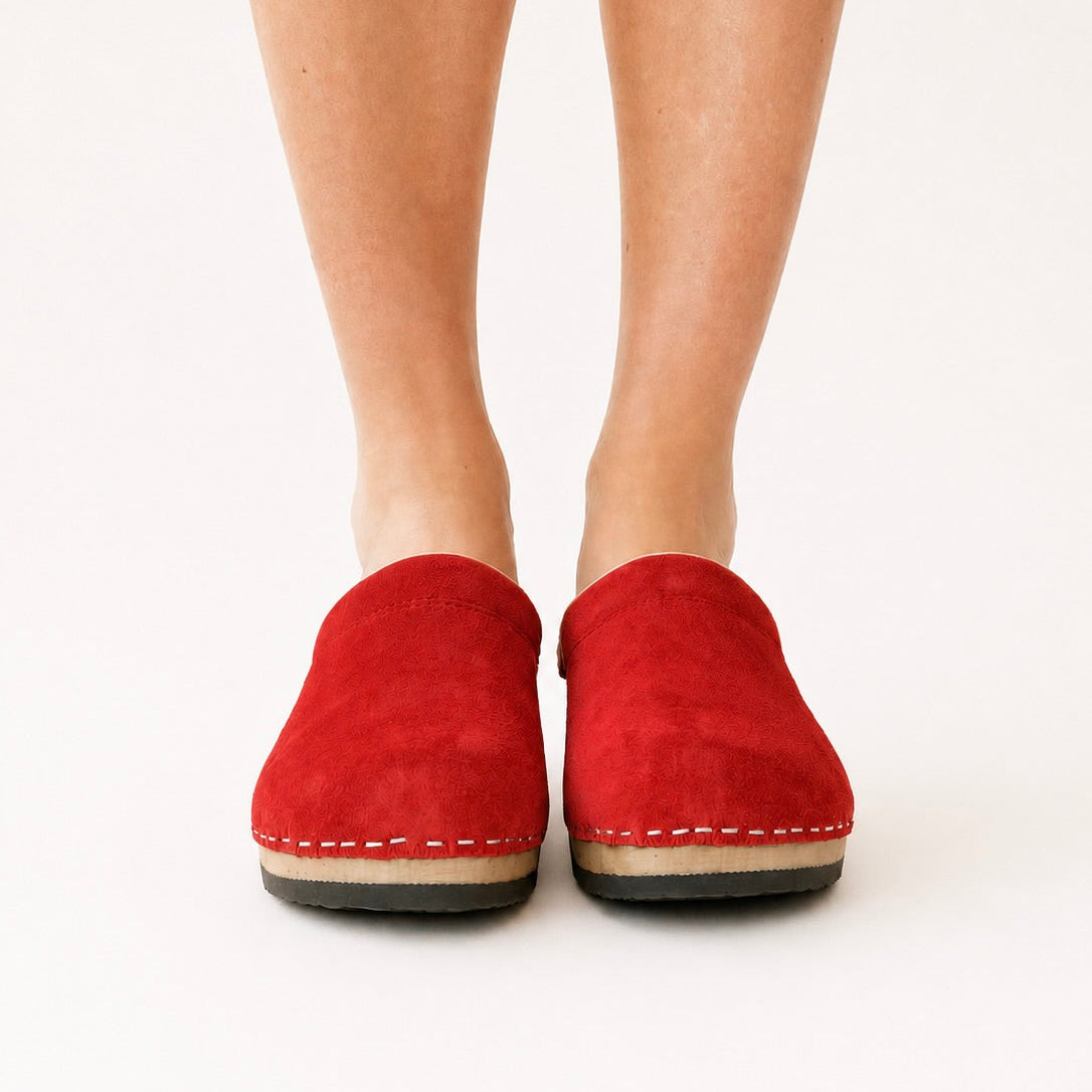 A vibrant red suede clog with a wooden sole and a soft collar, designed in Copenhagen and handmade in Sweden.