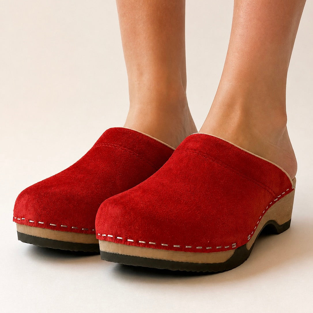 A vibrant red suede clog with a wooden sole and a soft collar, designed in Copenhagen and handmade in Sweden.