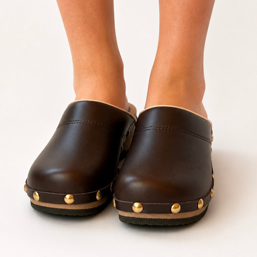 Black leather clog with wooden sole and gold studs on a white background