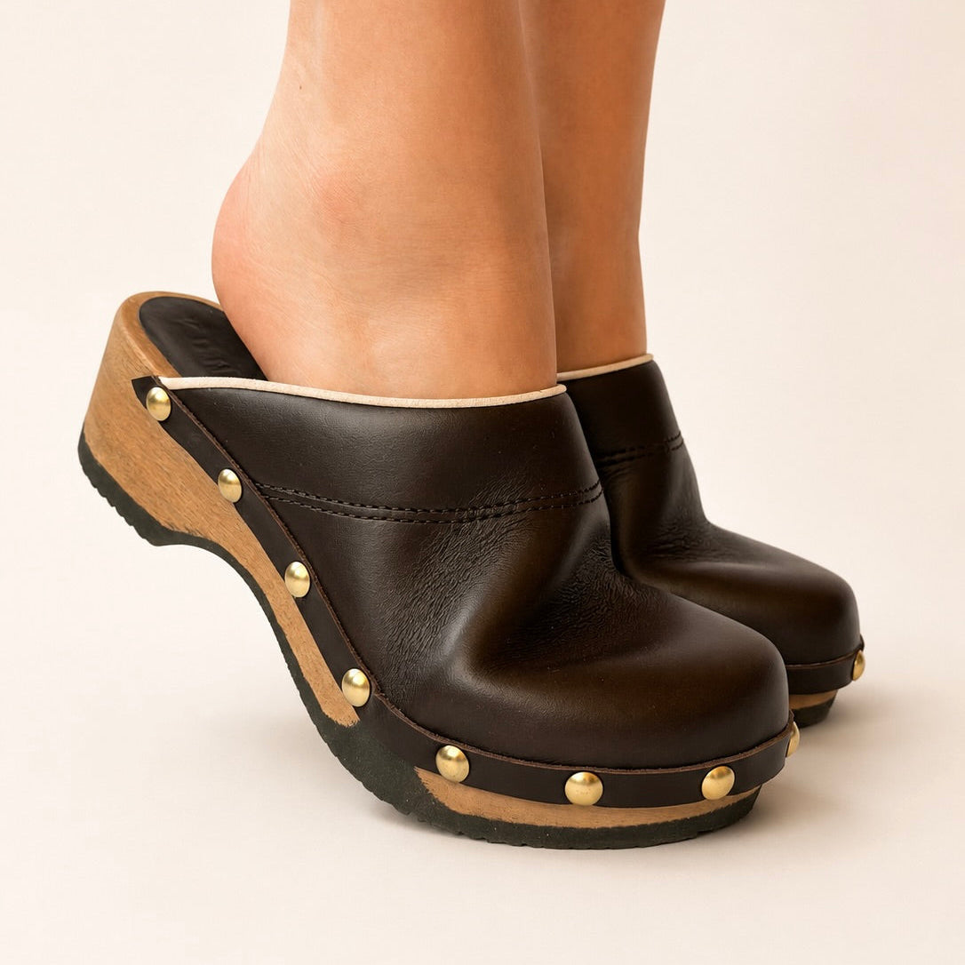 Pair of rich brown leather studs clogs on a white background
