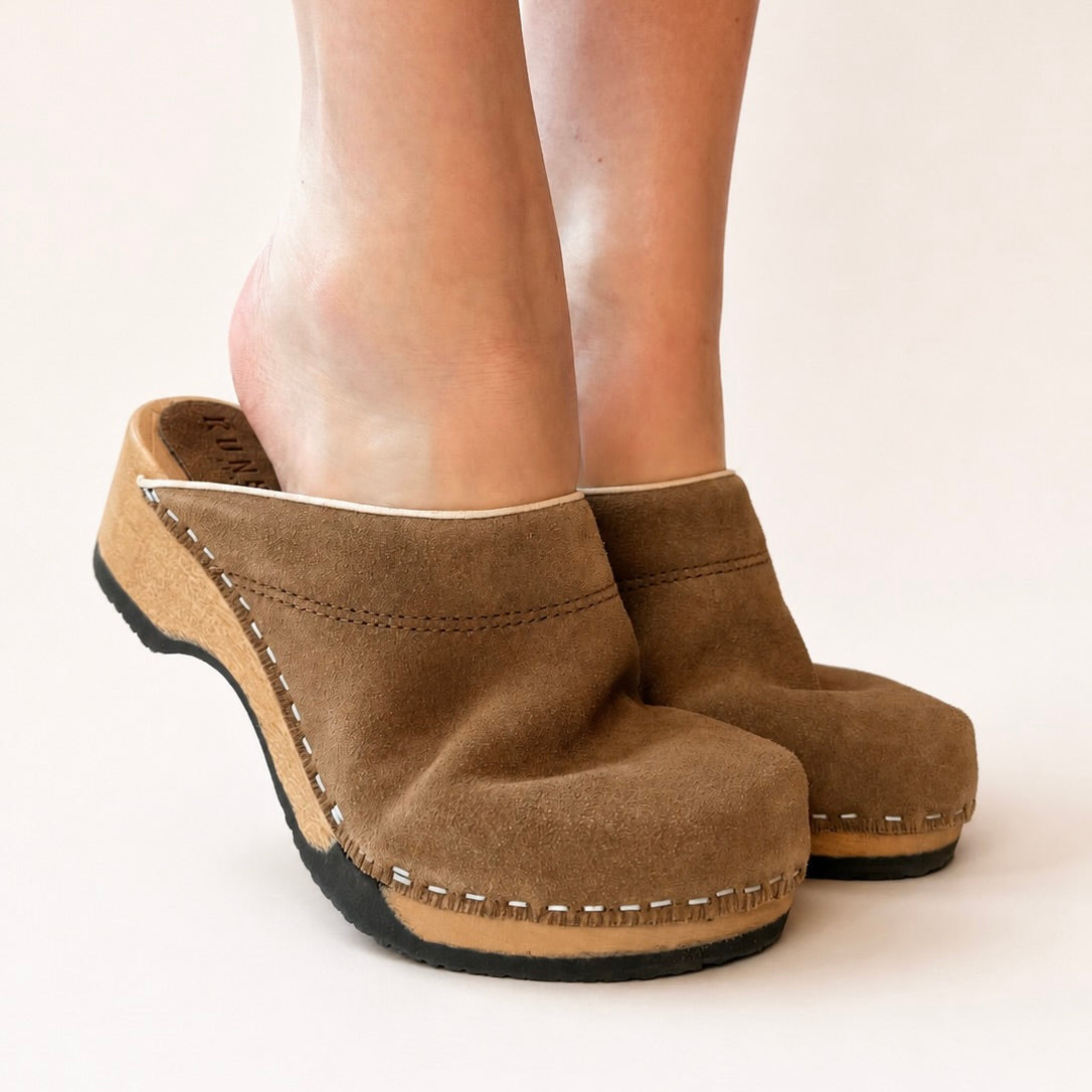 Pair of umber suede clogs on a white background