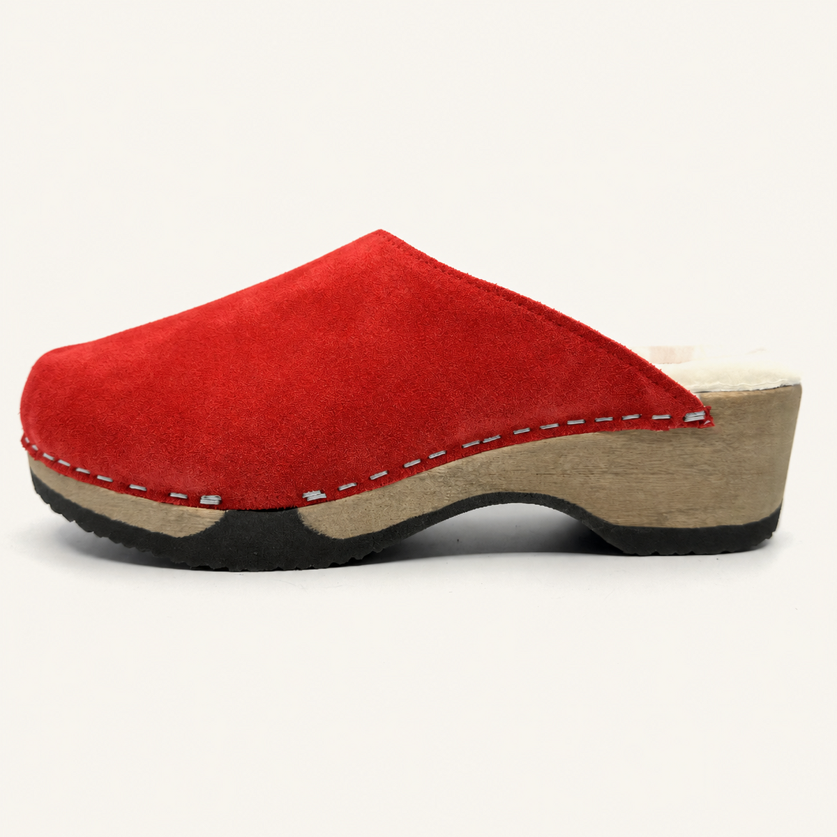 A red suede clog shoe with a natural wood wedge heel and a black outsole, shown from a side profile view against a light cream background.