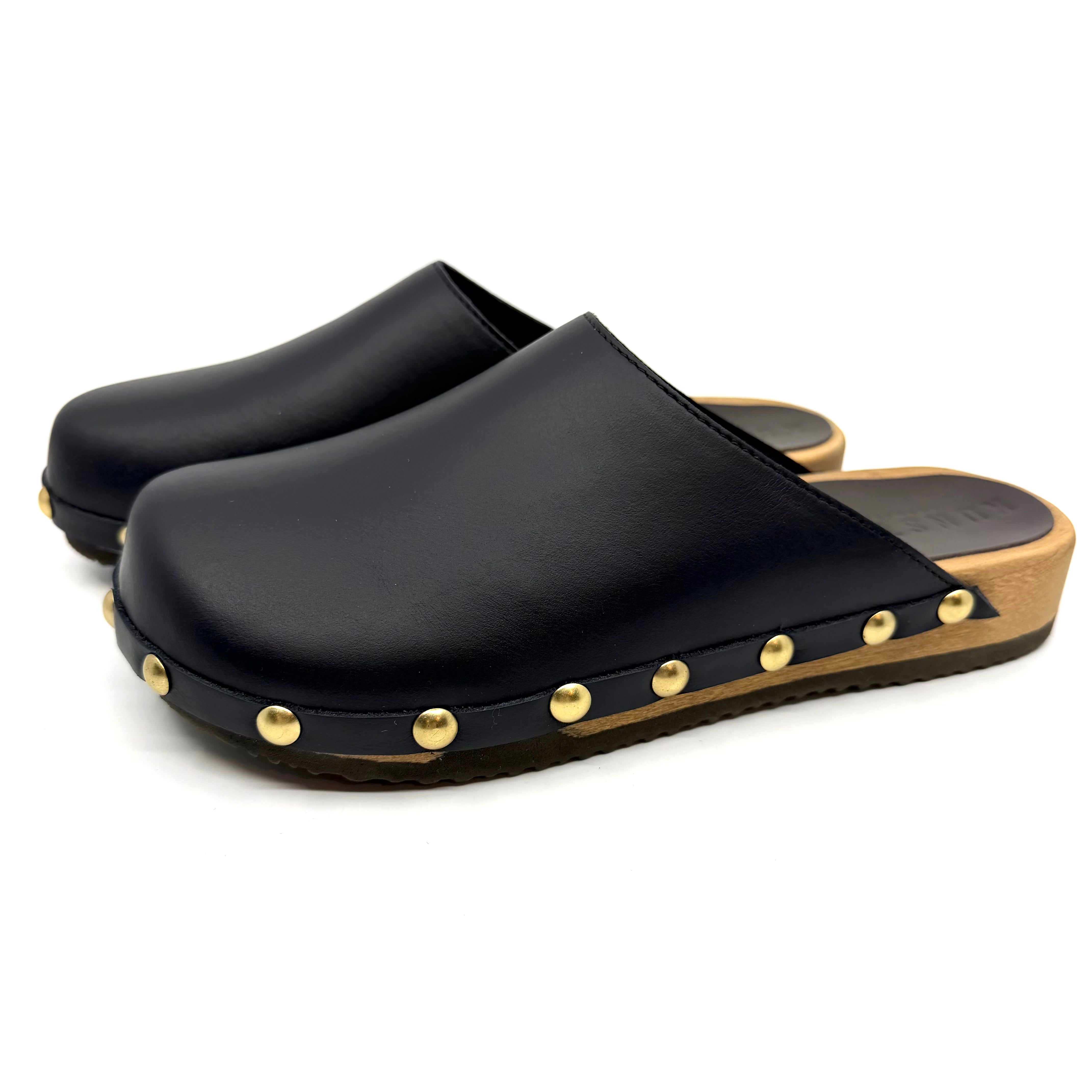 Black clogs with gold studs on a white background