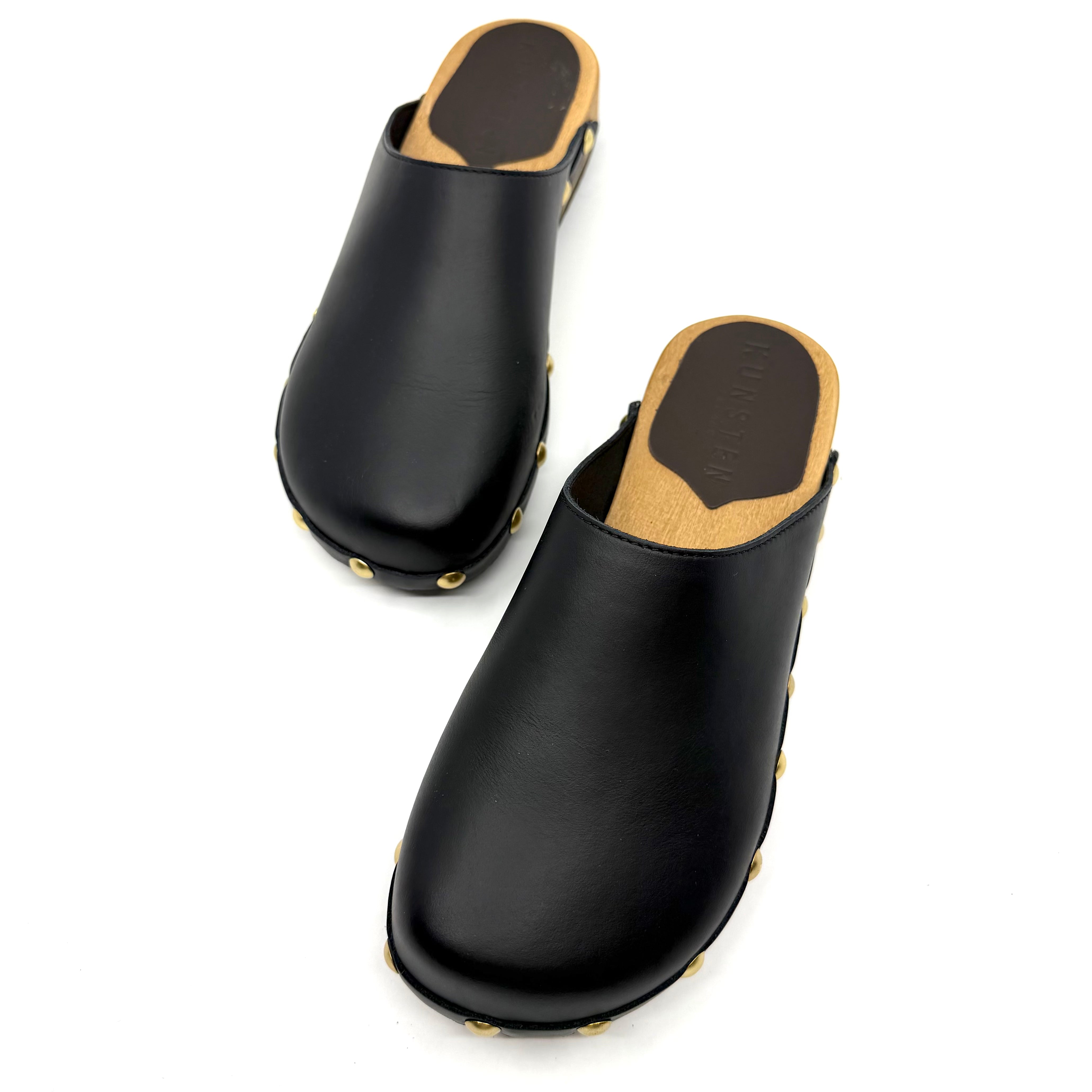 Pair of black clogs with tan insole on a white background