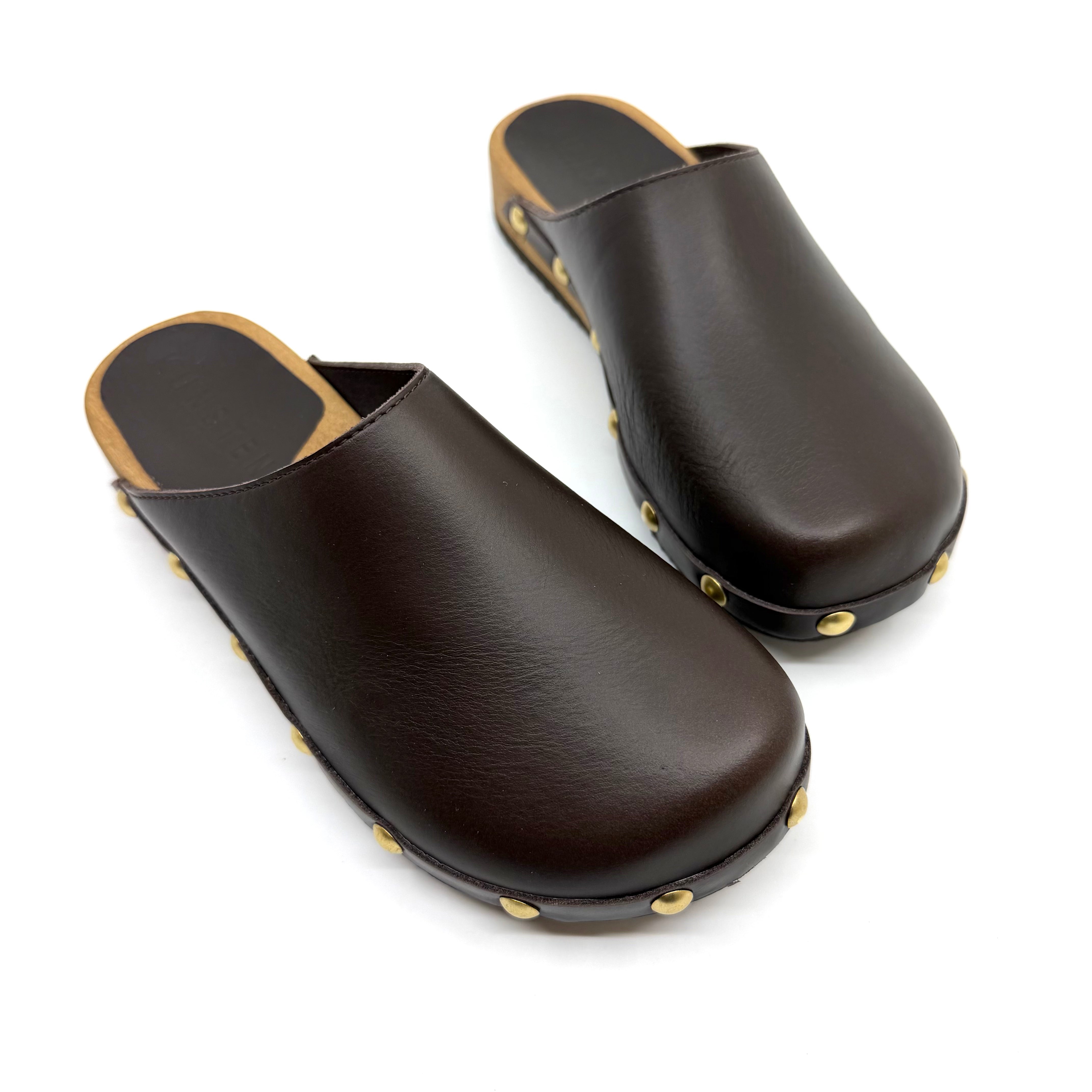 Pair of brown leather clogs with gold studs on a white background