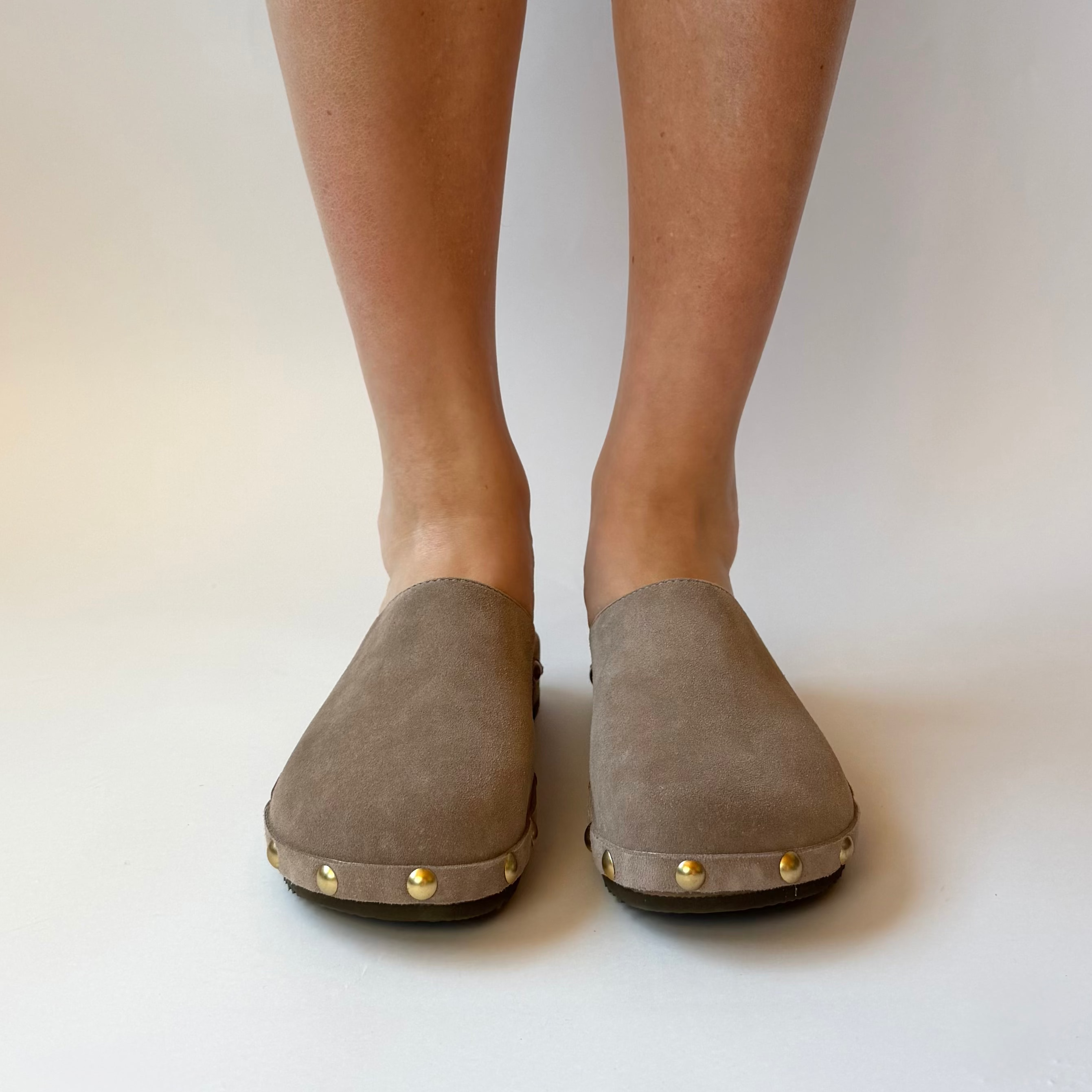 Gray suede shoes worn by a person on a plain background