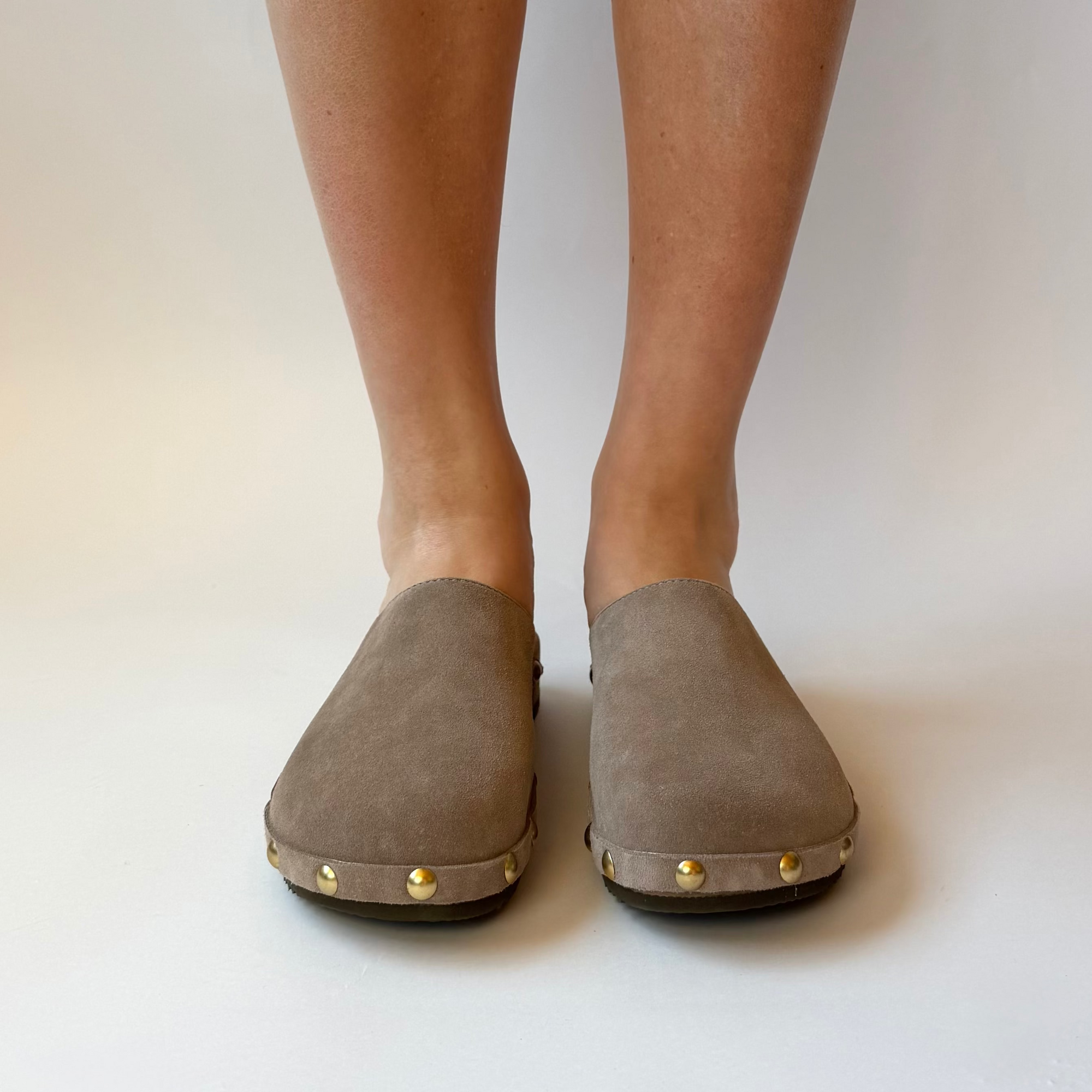 Gray suede shoes worn by a person on a plain background