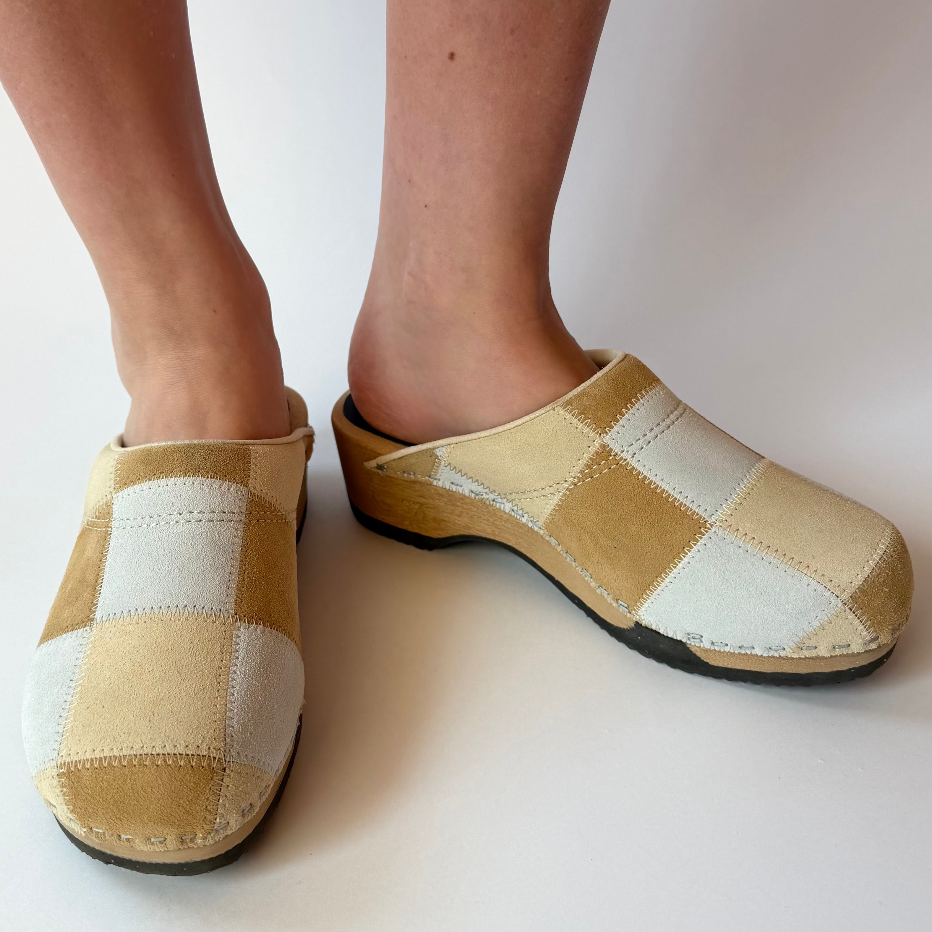 Checkered clogs worn by a person on a white background