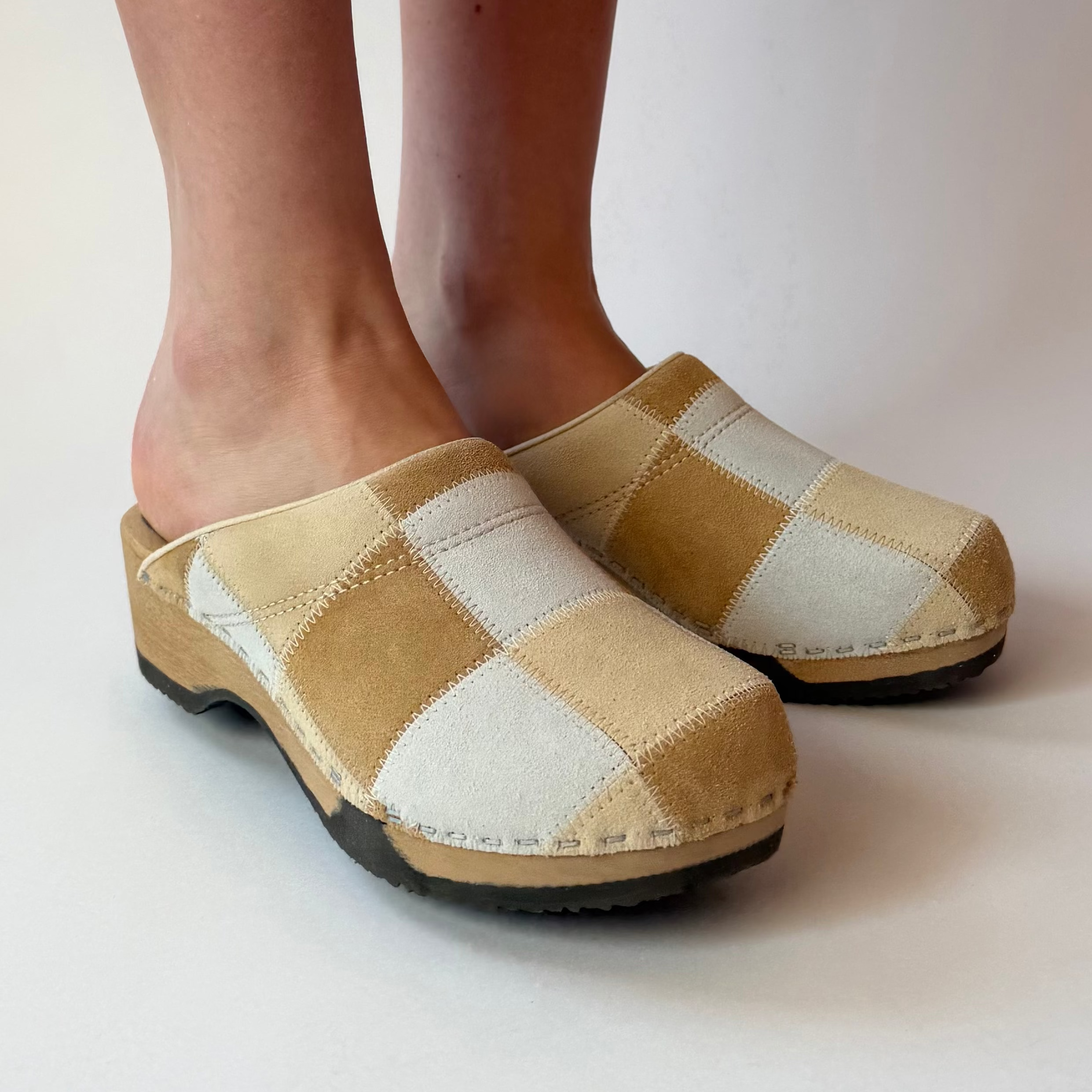 Checkered clogs worn by a person on a plain background