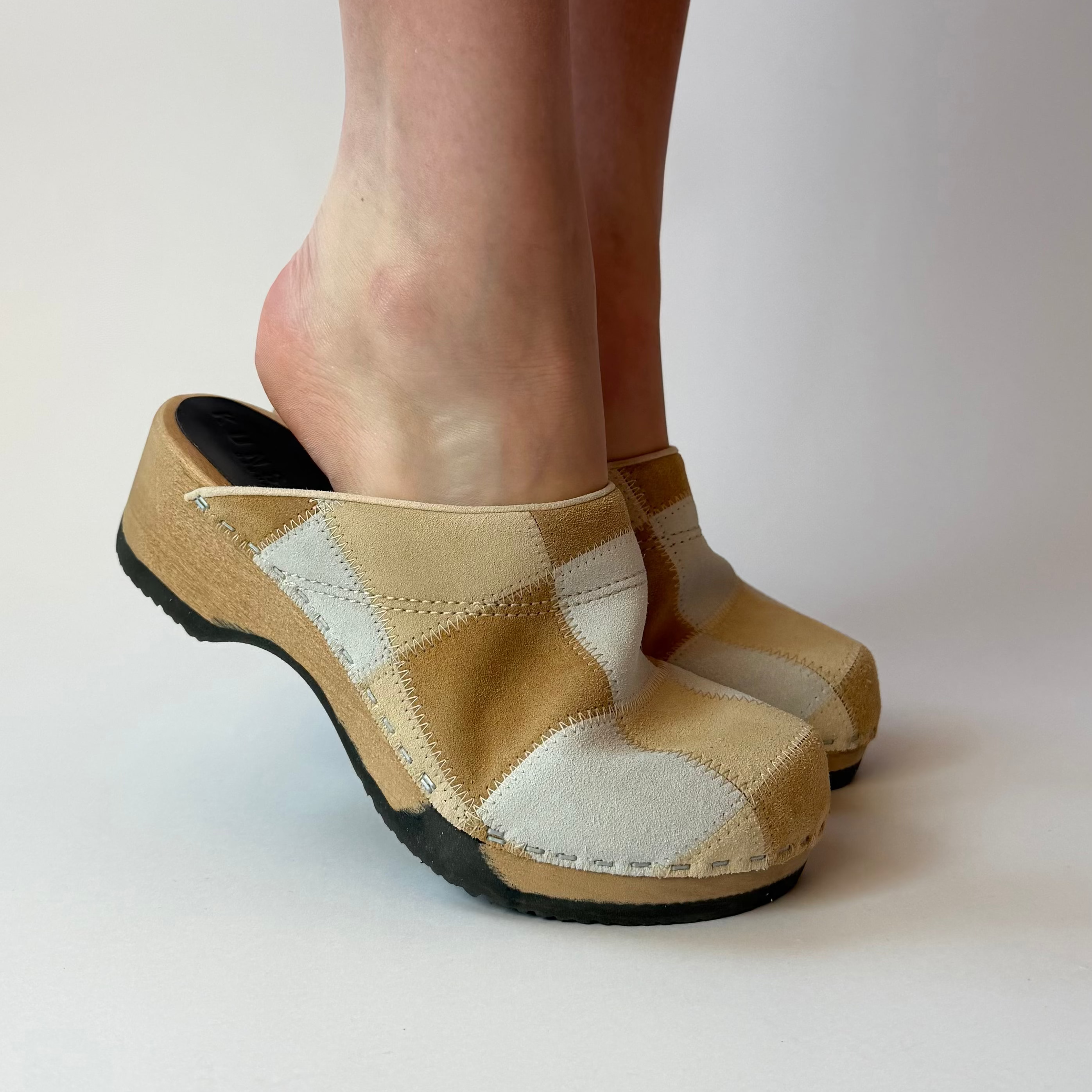 Beige checkered clogs worn by a person on a white background