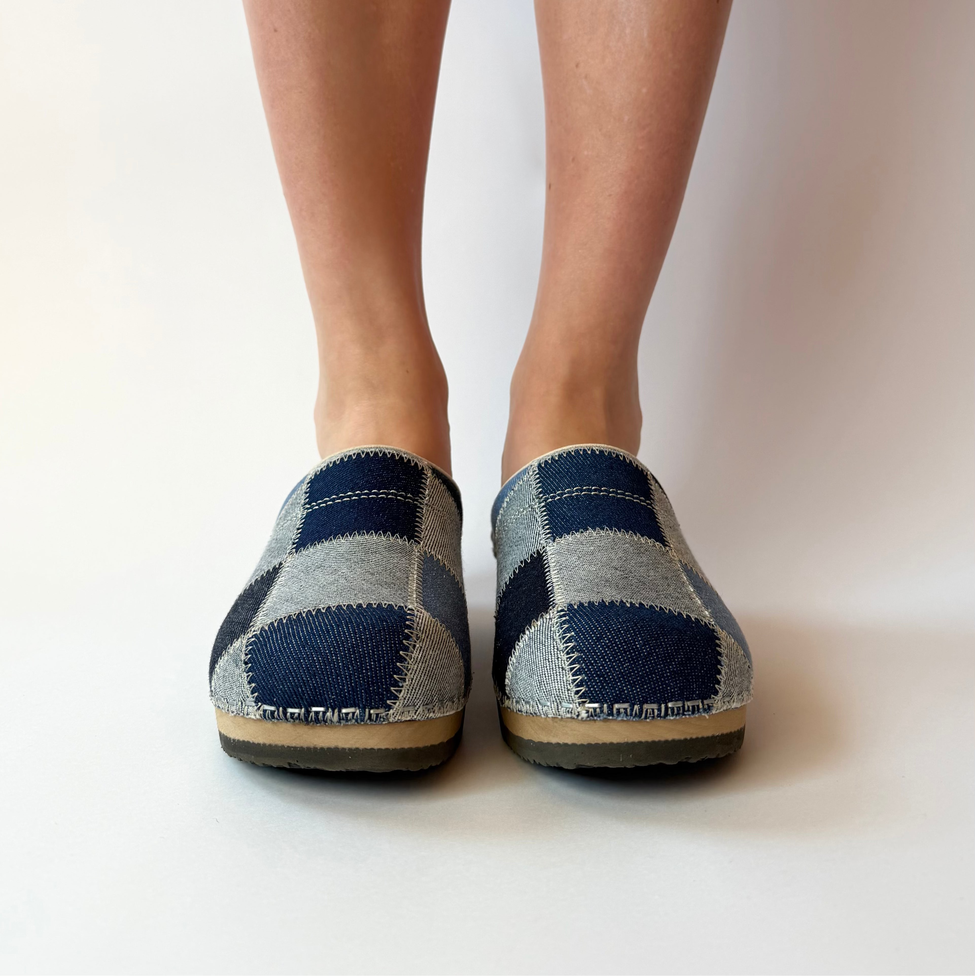 Blue and gray checkered slippers worn by a person on a white background