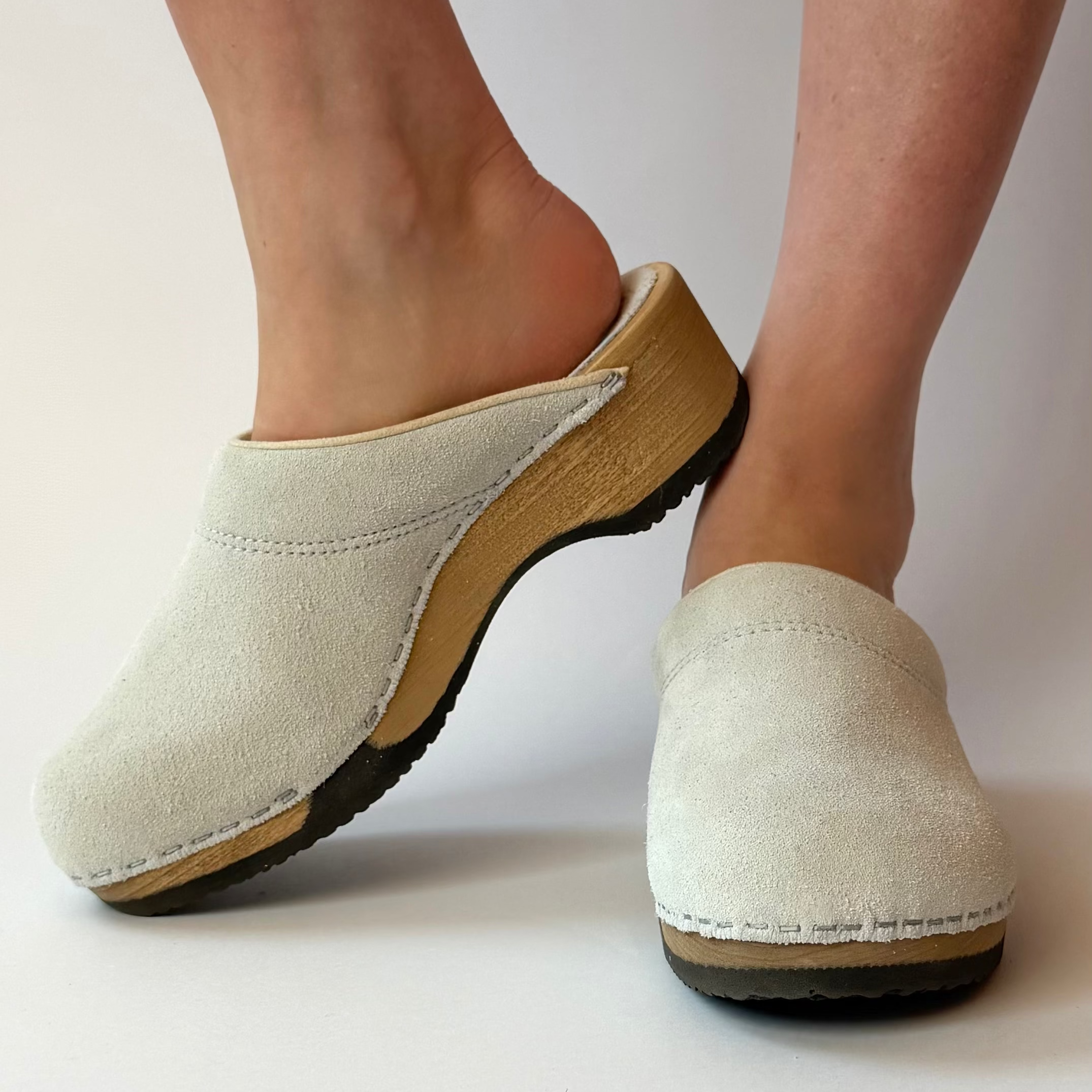 White clogs with brown soles on a white background