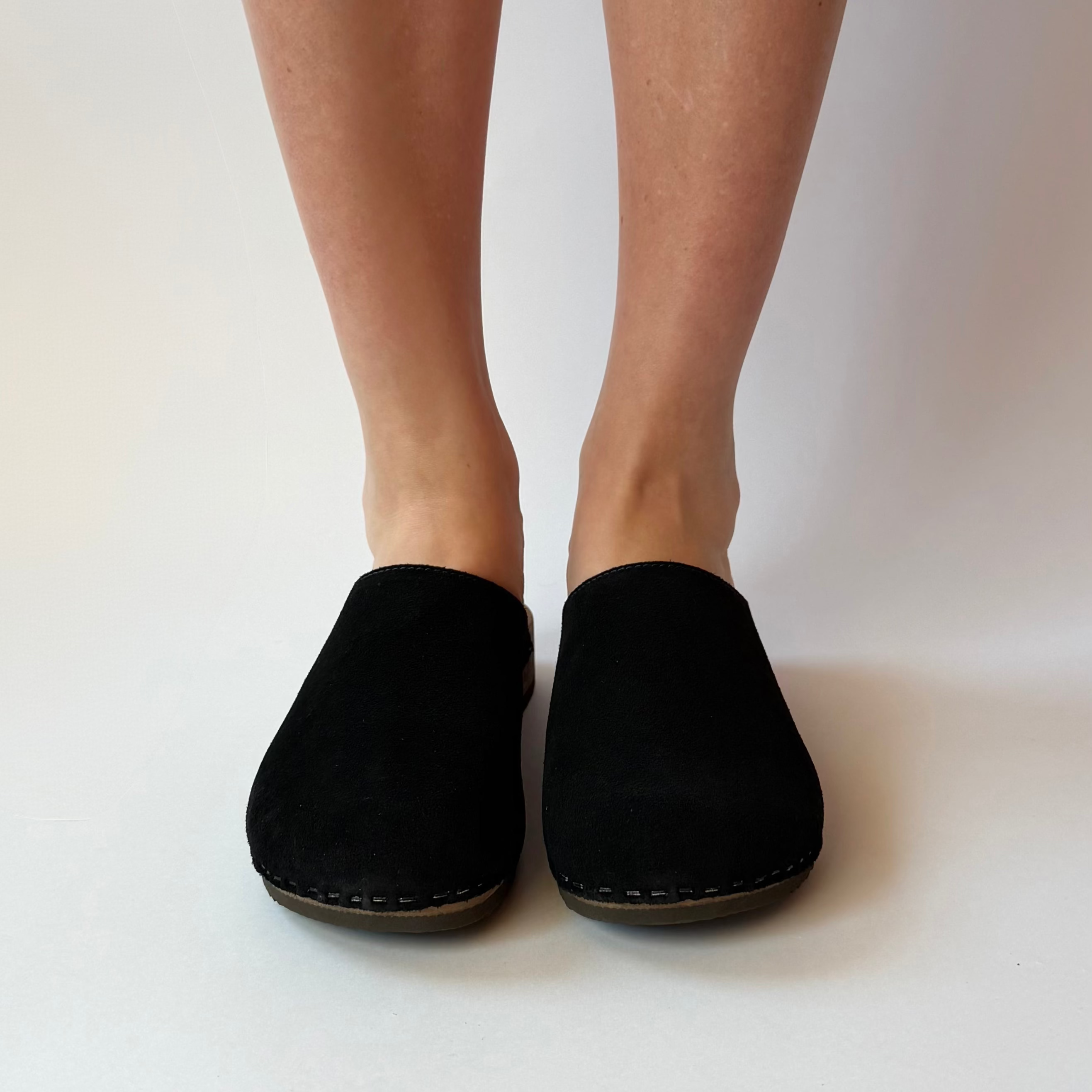 Black slippers worn by a person on a white background