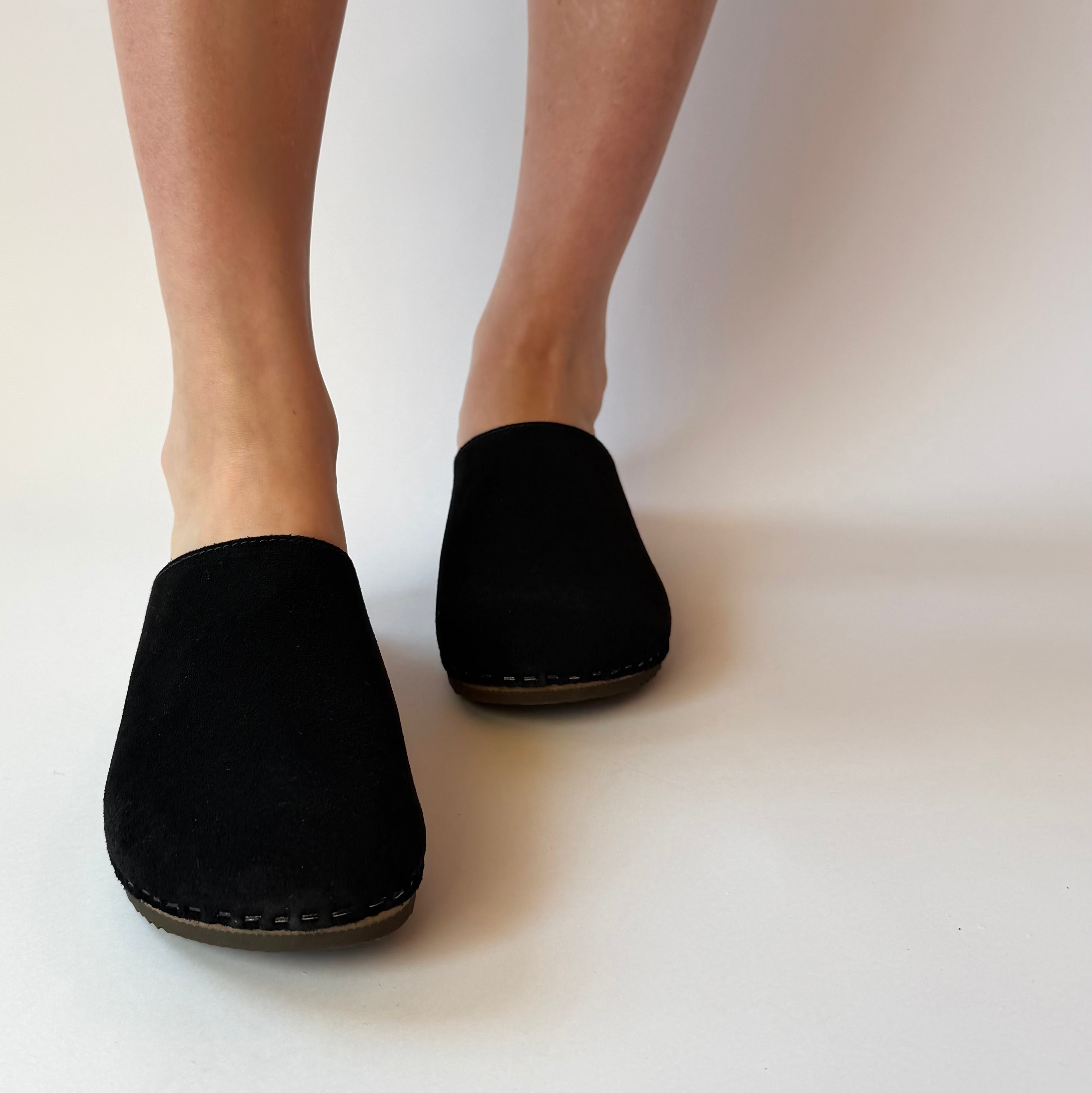 Black slippers worn by a person on a white background