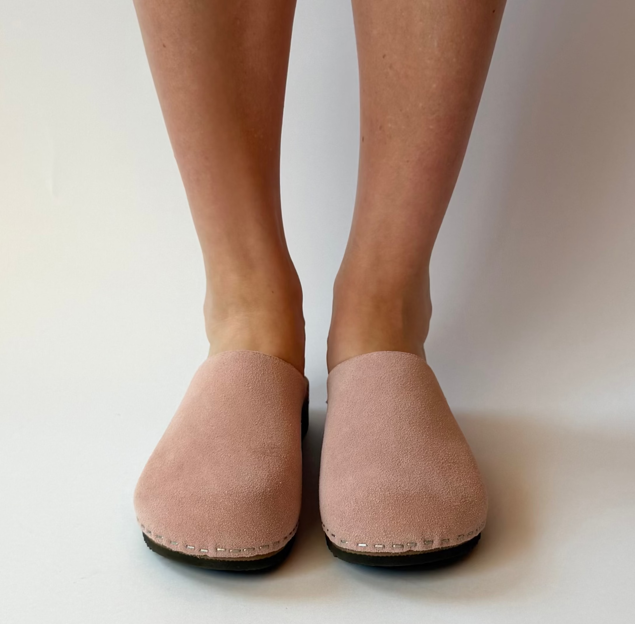 Person wearing pink slippers on a plain background