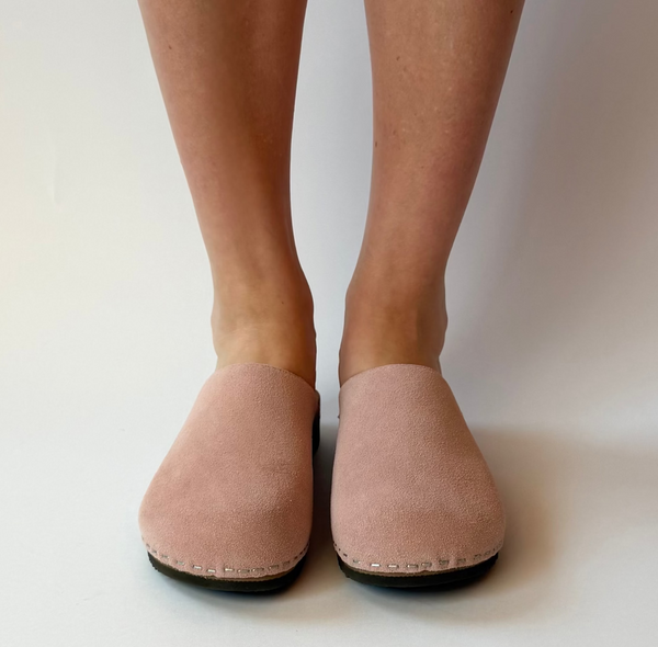 Person wearing pink slippers on a plain background