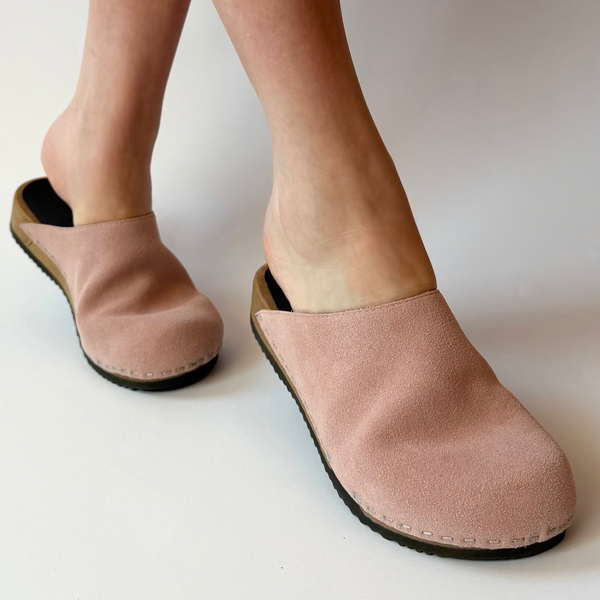 Pink slippers worn by a person on a white background